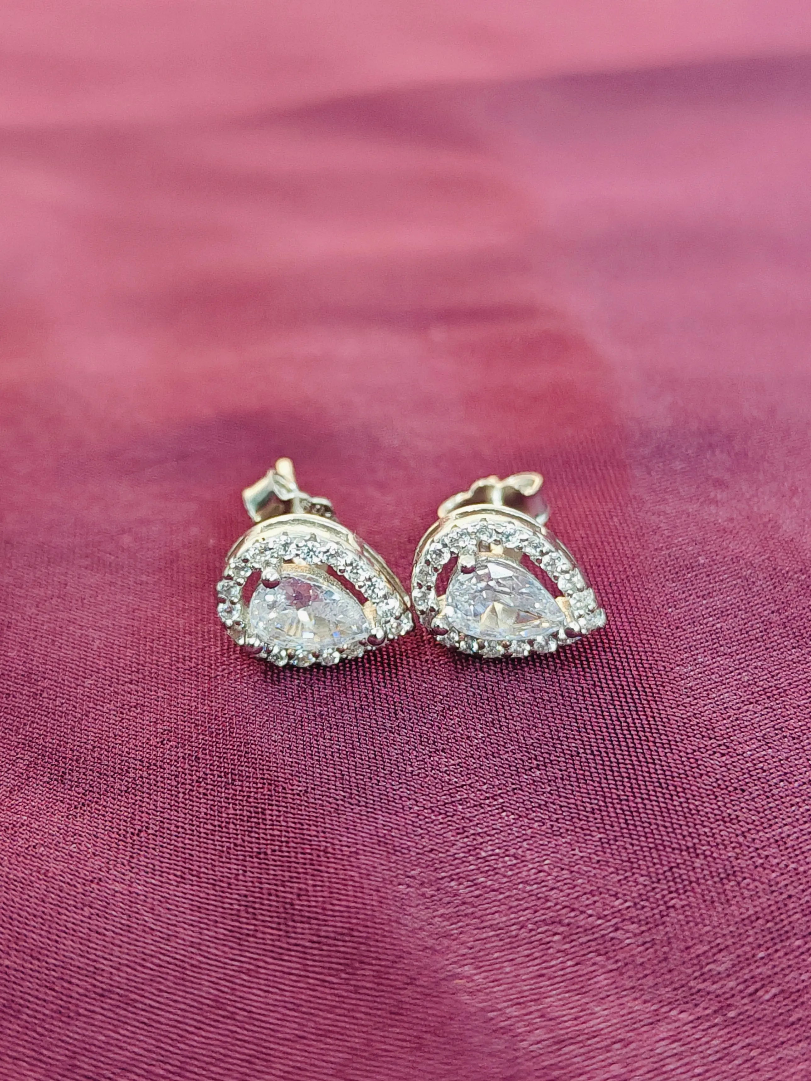 Pair of diamond earrings on a pink fabric background