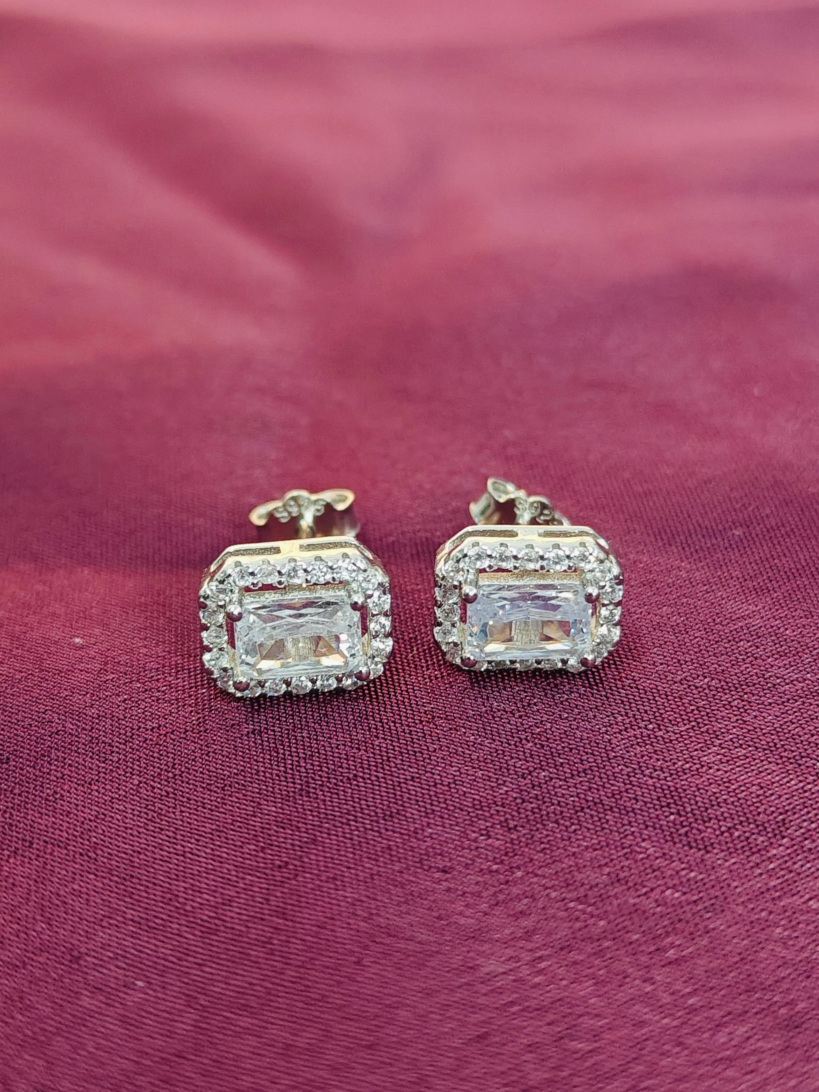 Pair of diamond earrings on a pink fabric background