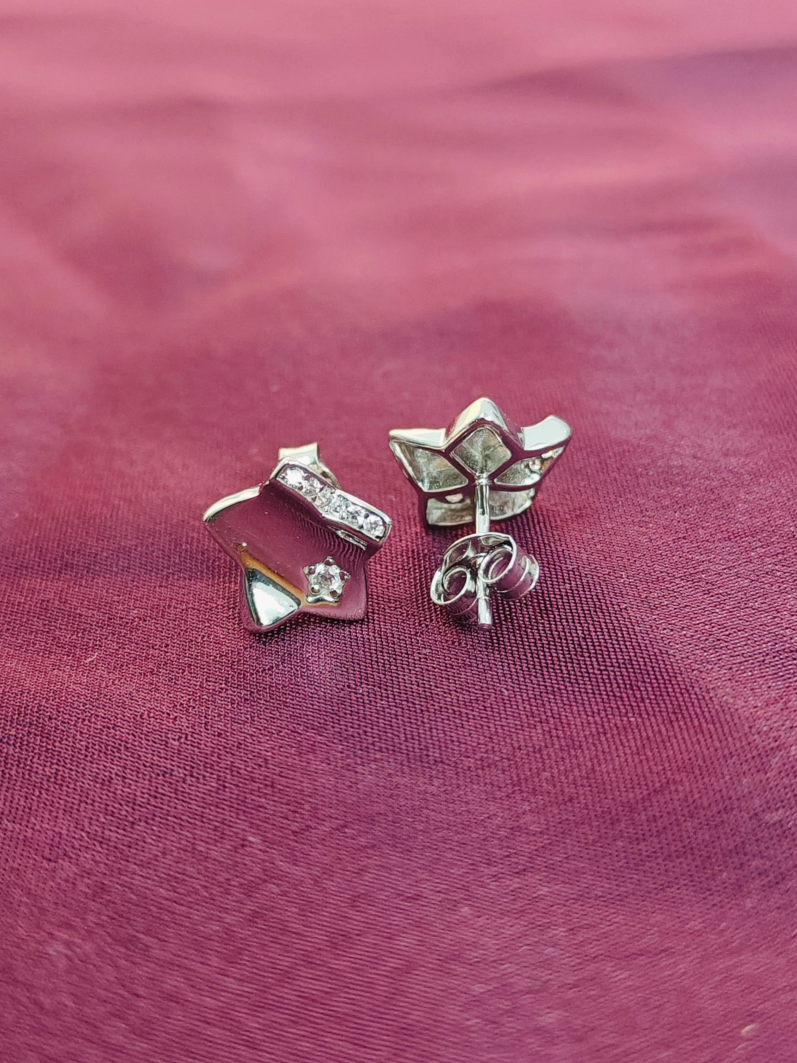 Three silver earrings on a maroon fabric background
