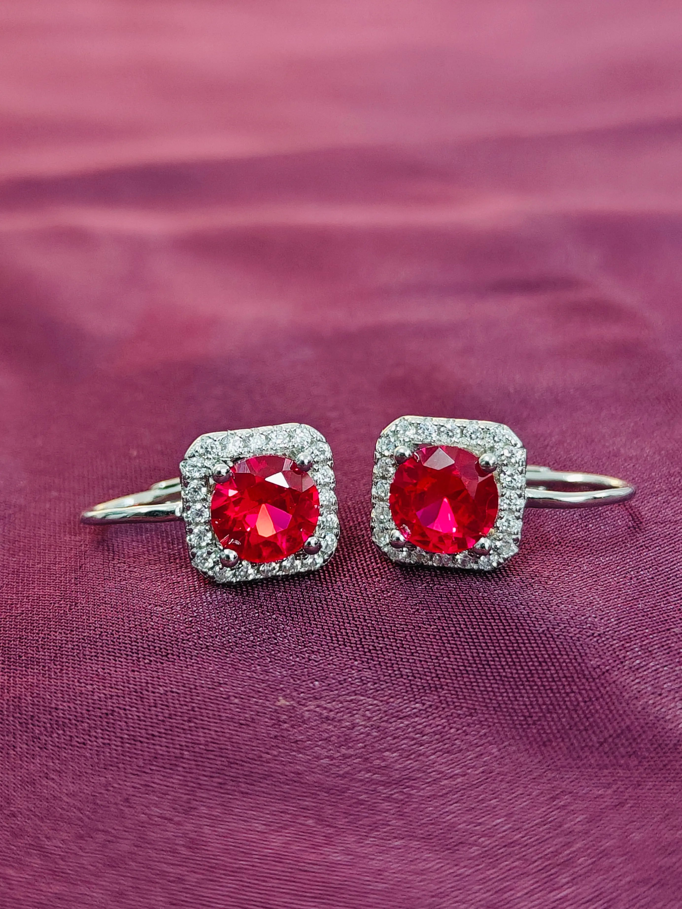 Pair of earrings with red gemstones on a purple fabric background