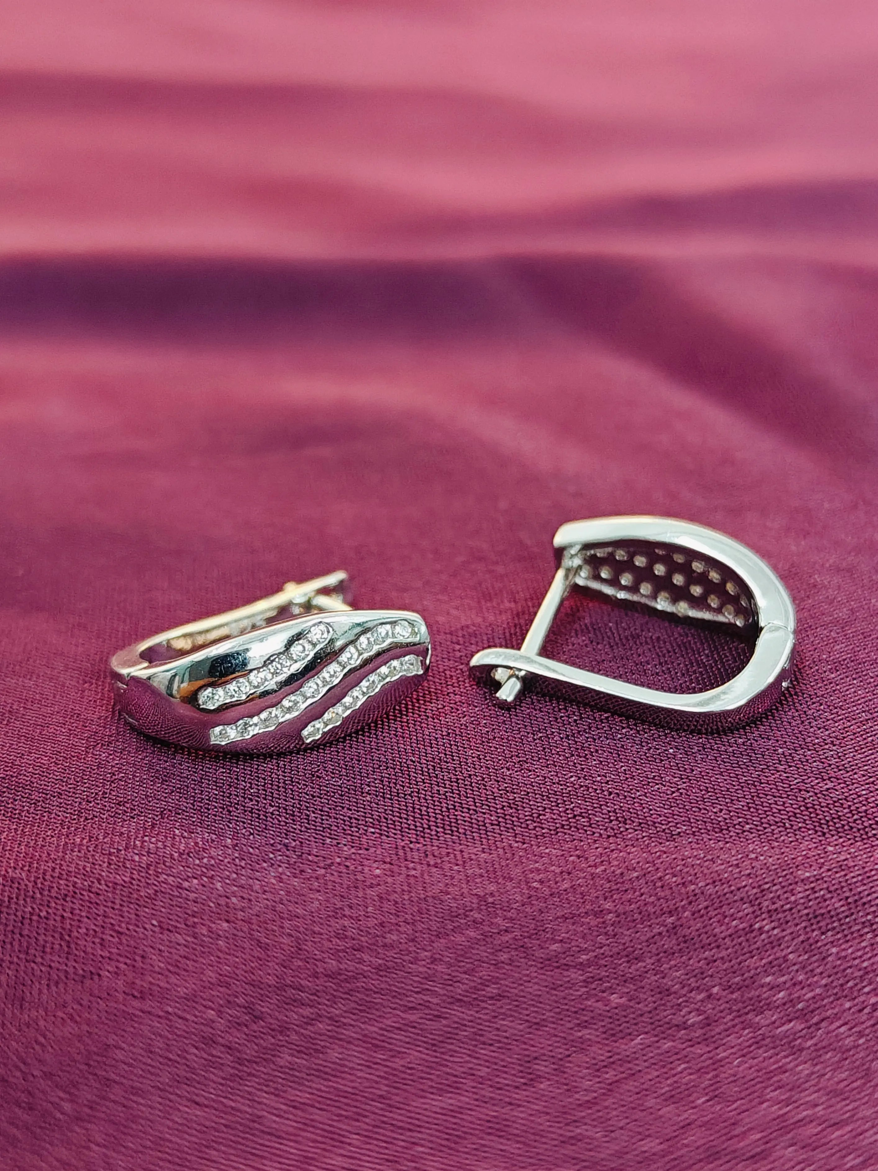 Silver earring on a purple fabric background