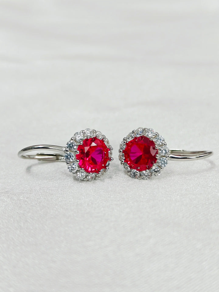 Pair of earrings with red gemstones on a light gray background