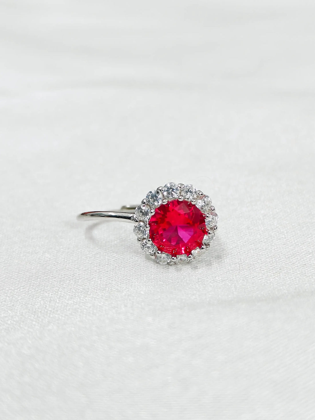 Silver ring with a red gemstone on a light gray background