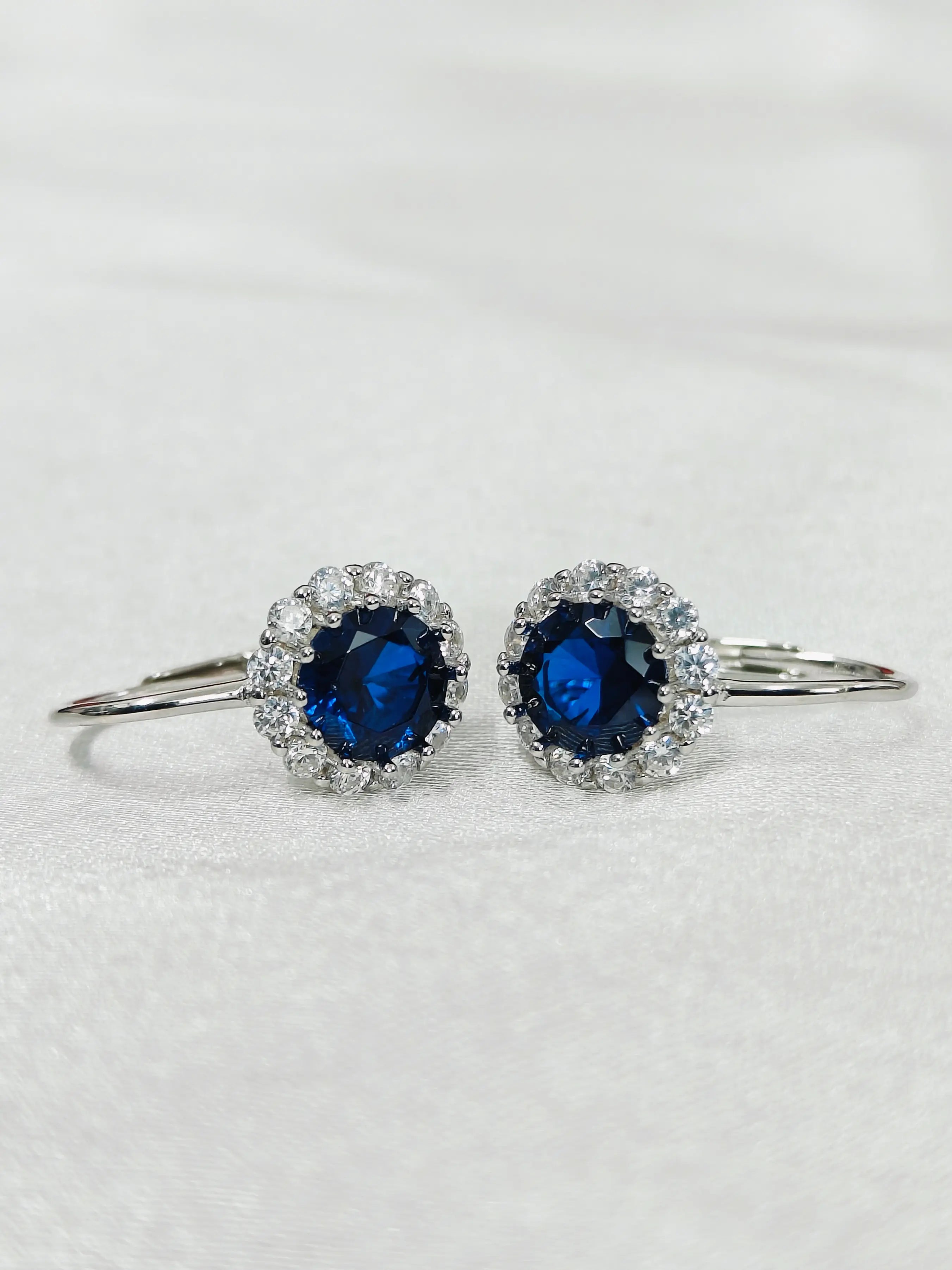Pair of silver earrings with blue gemstones on a light gray background