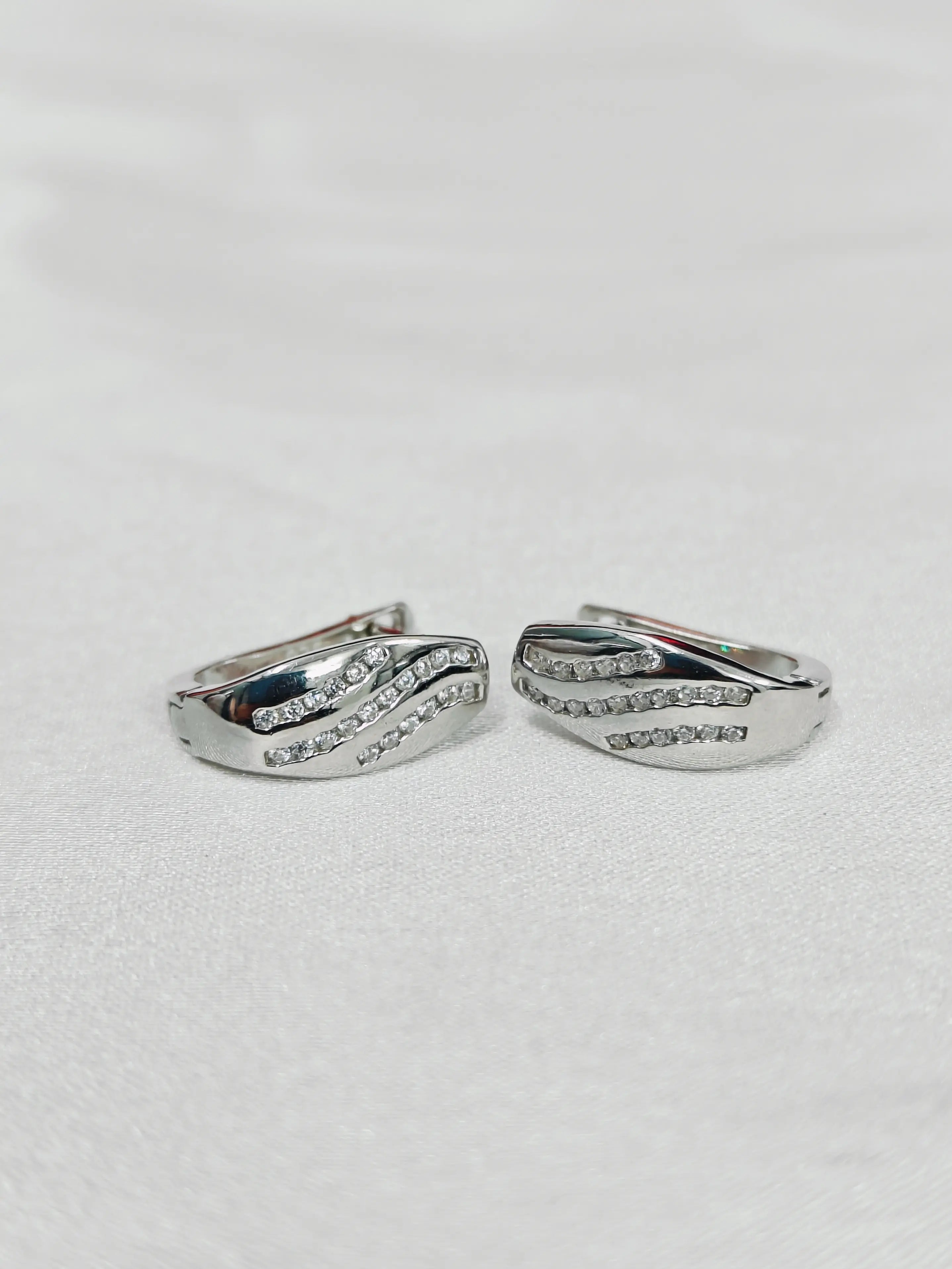 Pair of silver hoop earrings with small stones on a light gray background