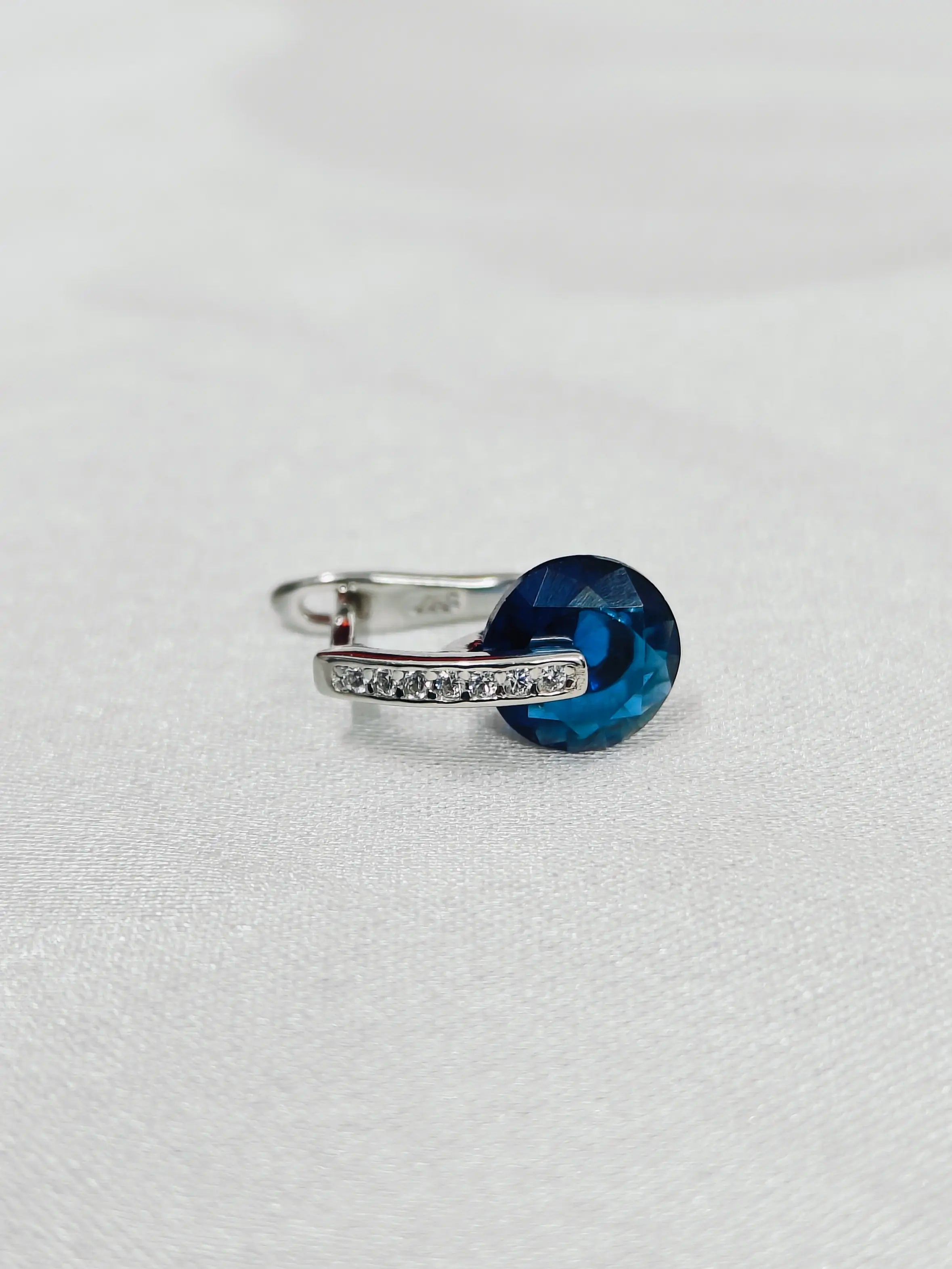 Silver ring with a blue gemstone on a white background