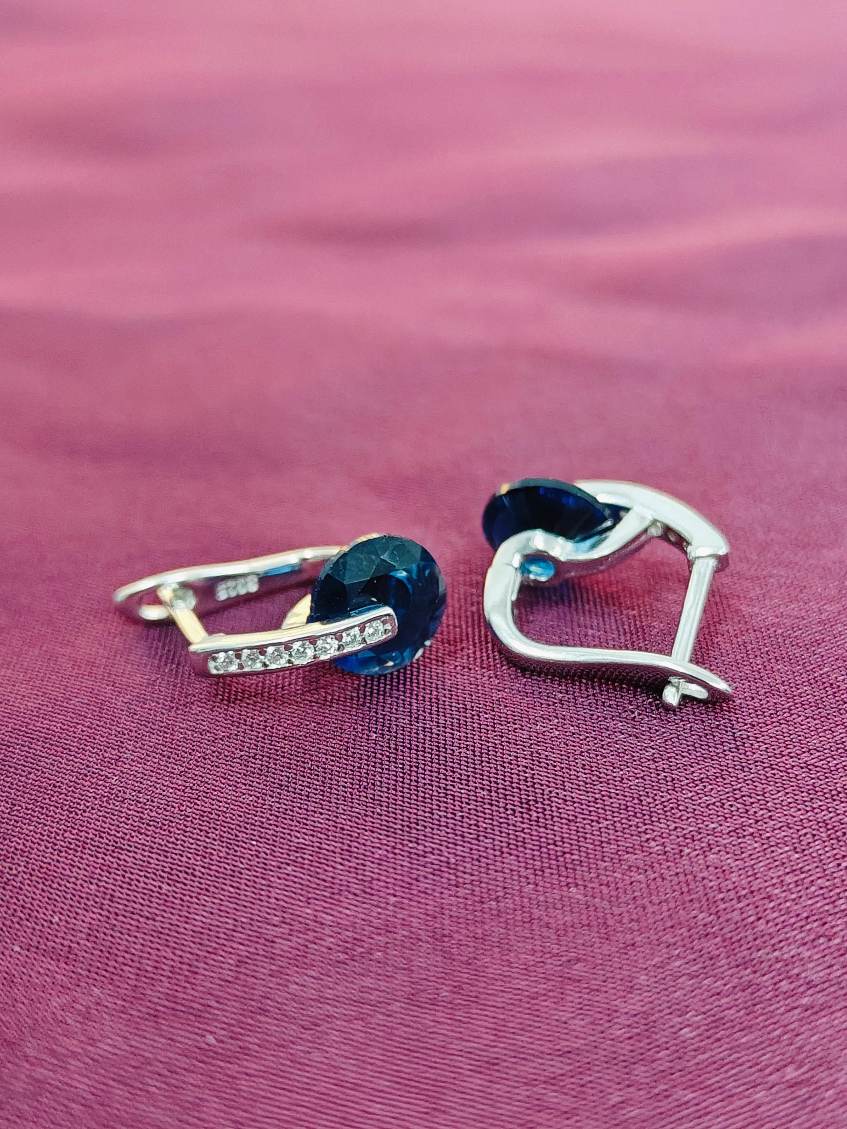Pair of earrings with blue gemstones on a pink fabric background