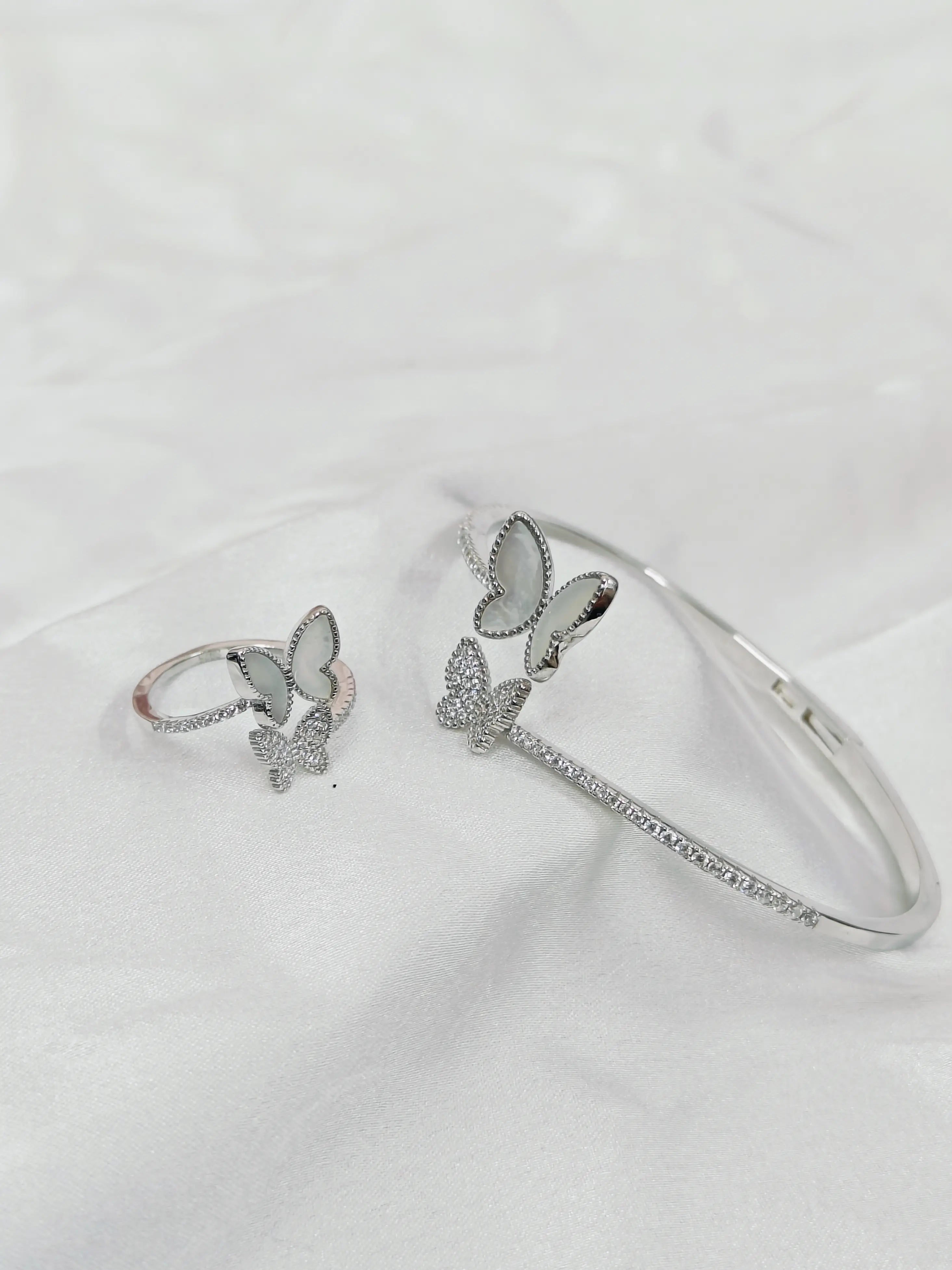 Silver butterfly-themed ring and bracelet on a white background