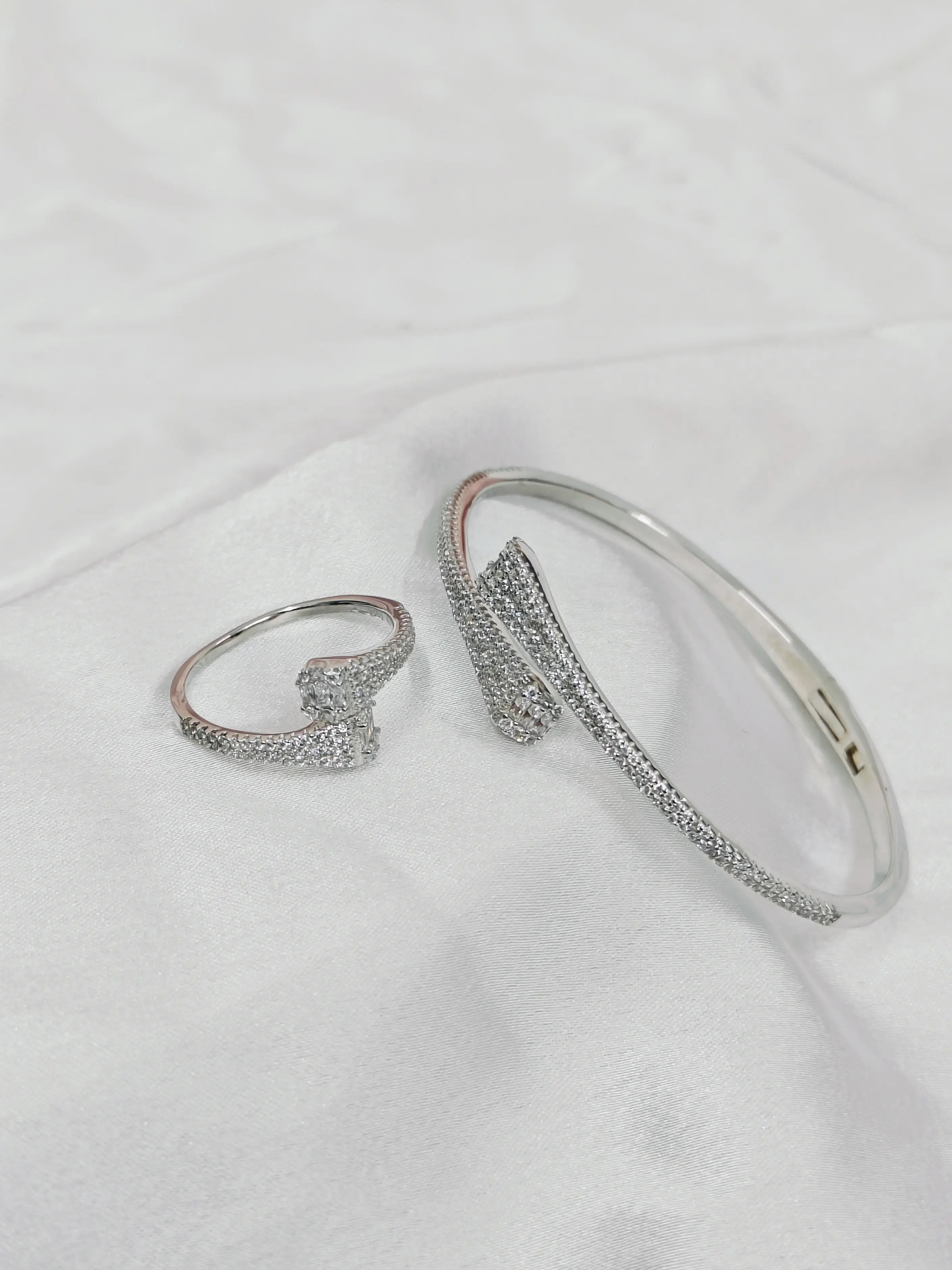 Silver ring and bracelet on a white fabric background