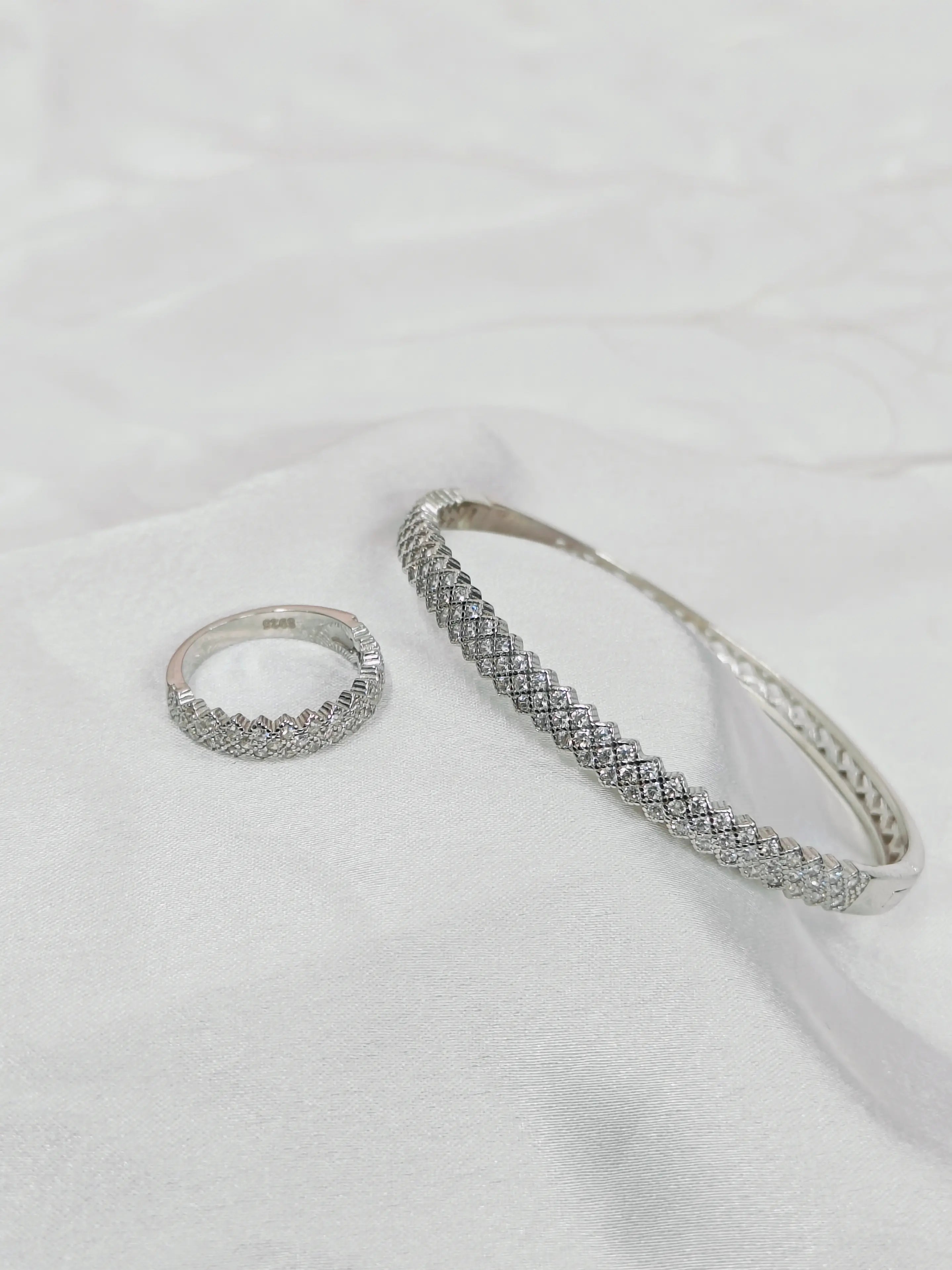Silver ring and bracelet set on a white fabric background