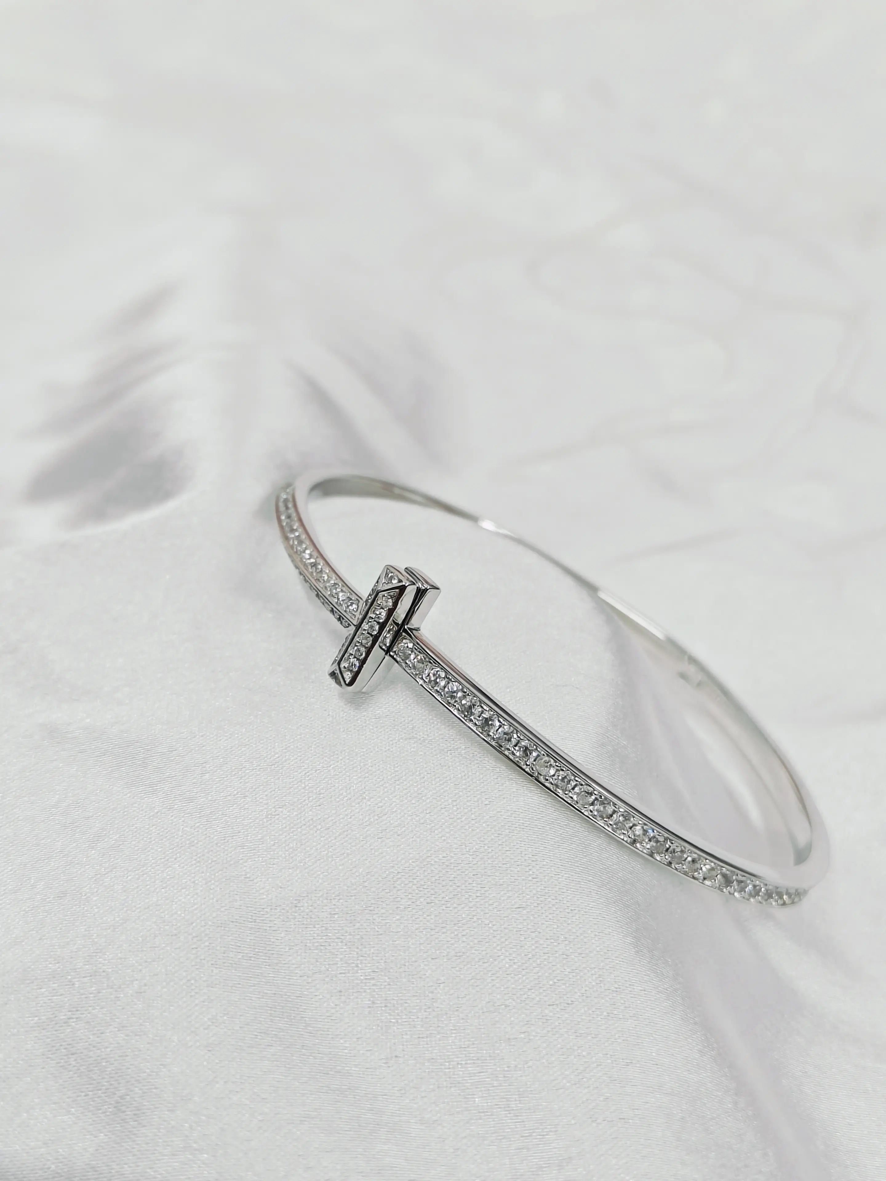 Silver bracelet with a clasp on a white fabric background
