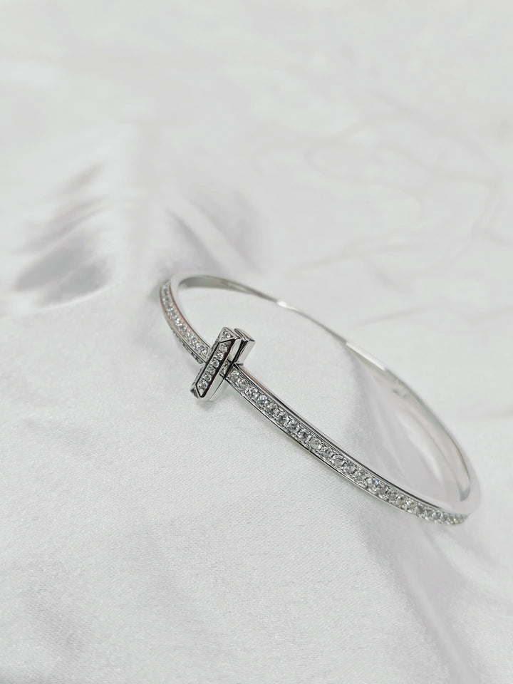 Silver bracelet with a clasp on a white fabric background