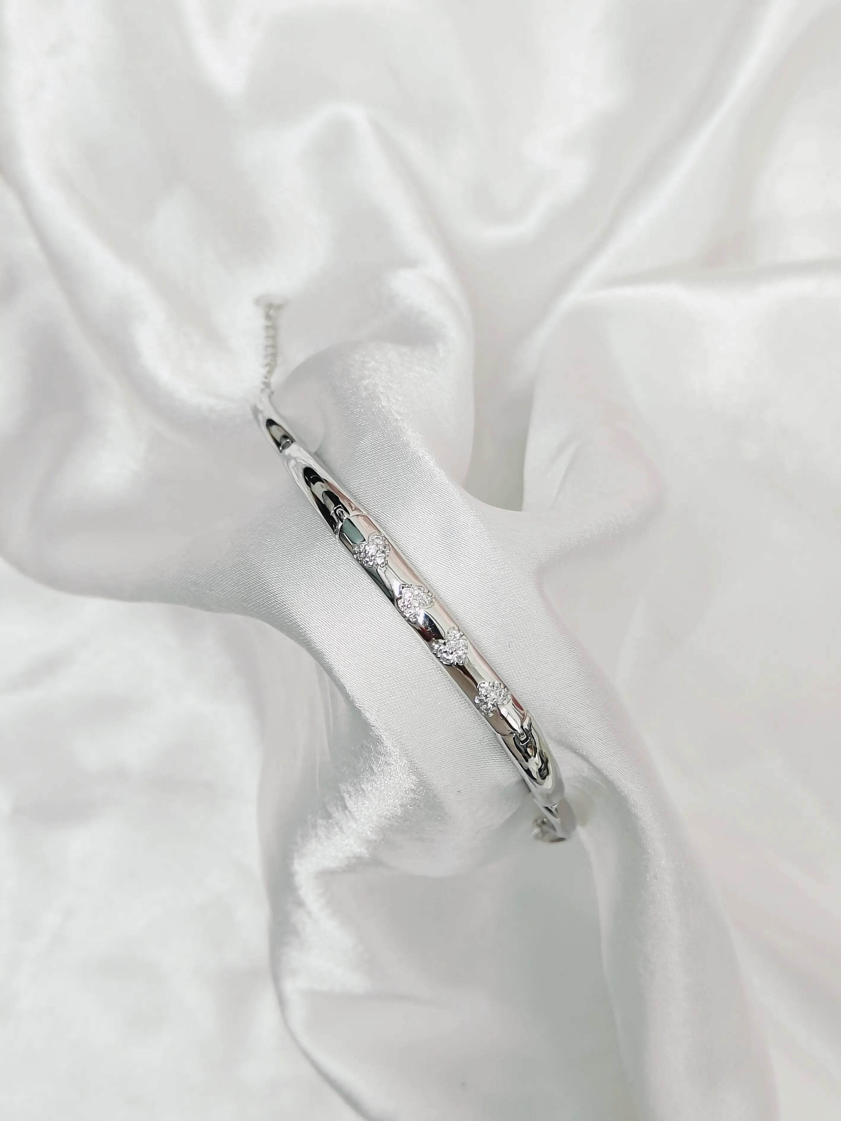 Silver bracelet with small stones on a white fabric background