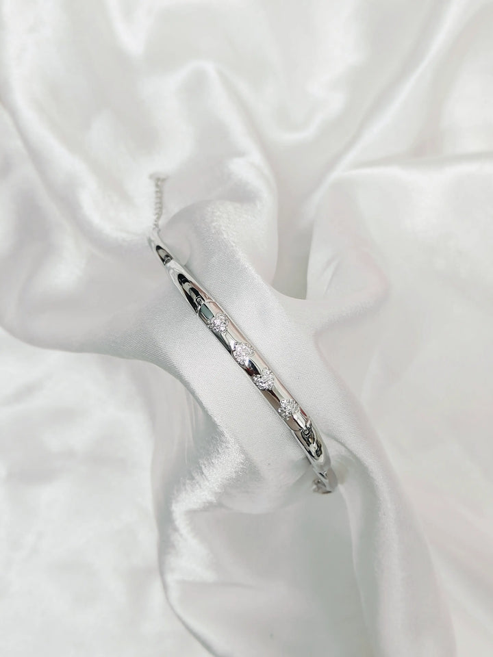 Silver bracelet with small stones on a white fabric background