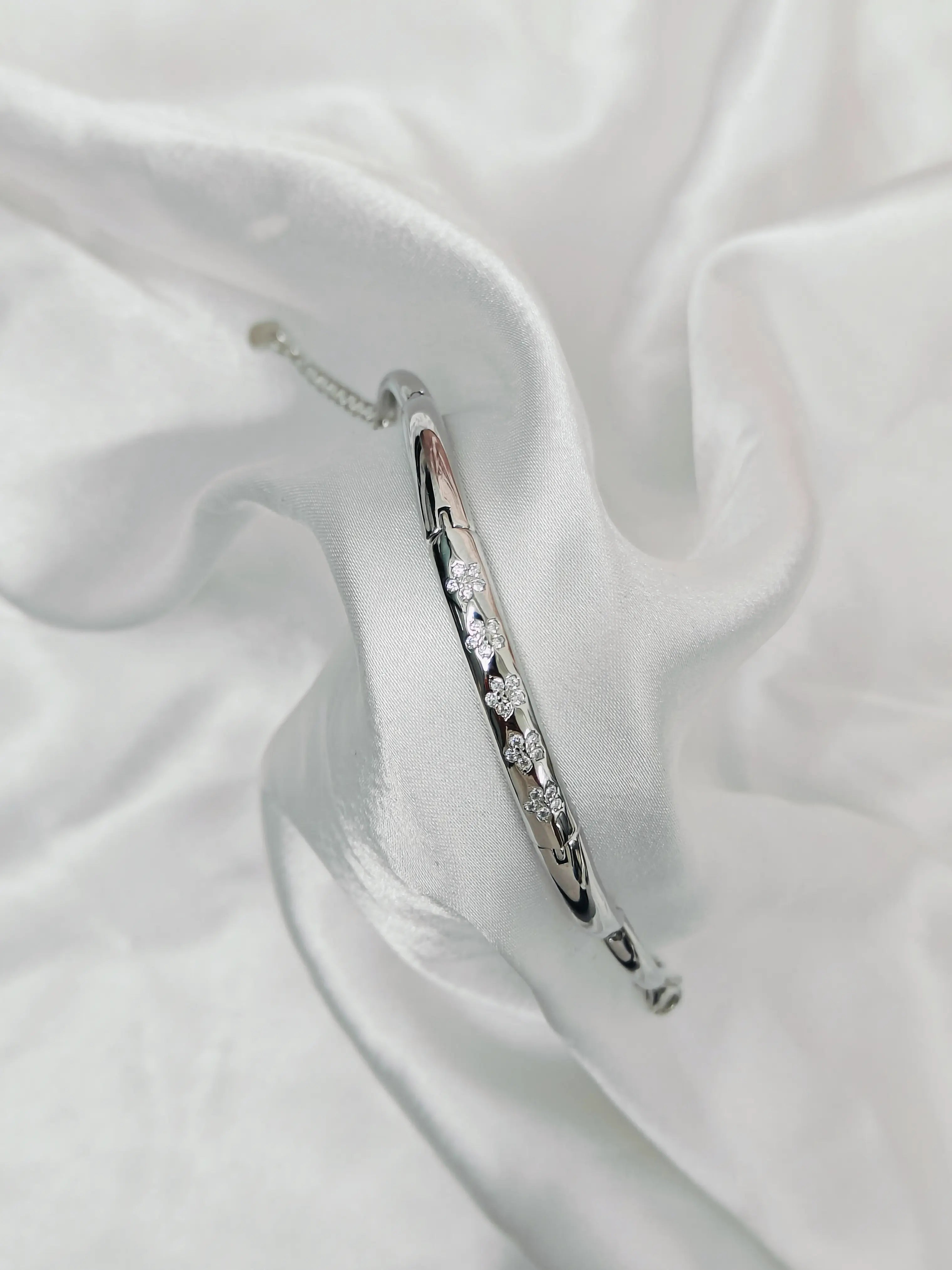 Silver bracelet with clear stones on a white fabric background