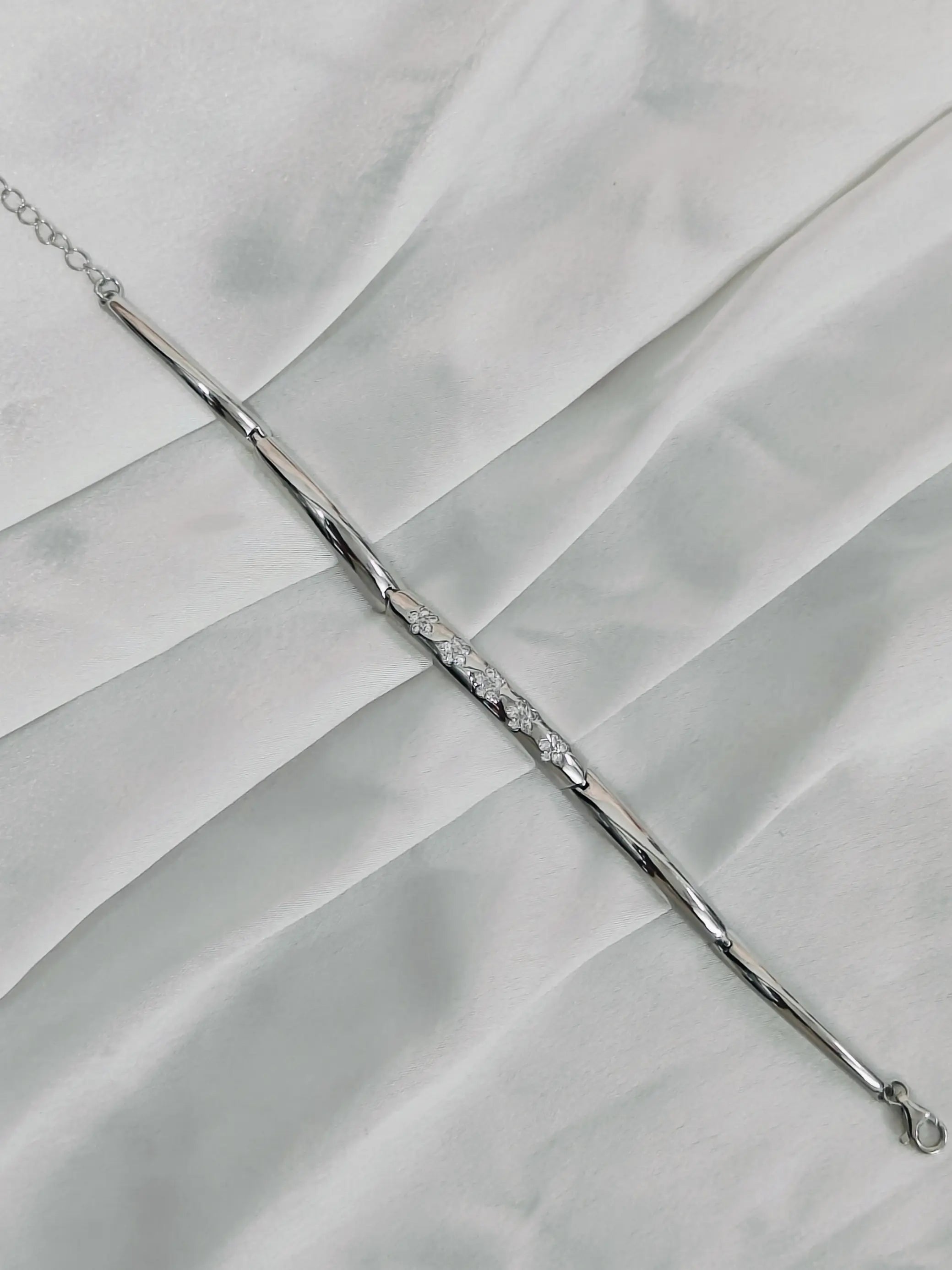 Silver bracelet with clear stones on a white fabric background