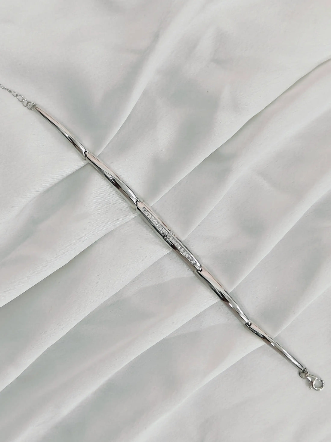 Silver bracelet on a white fabric background