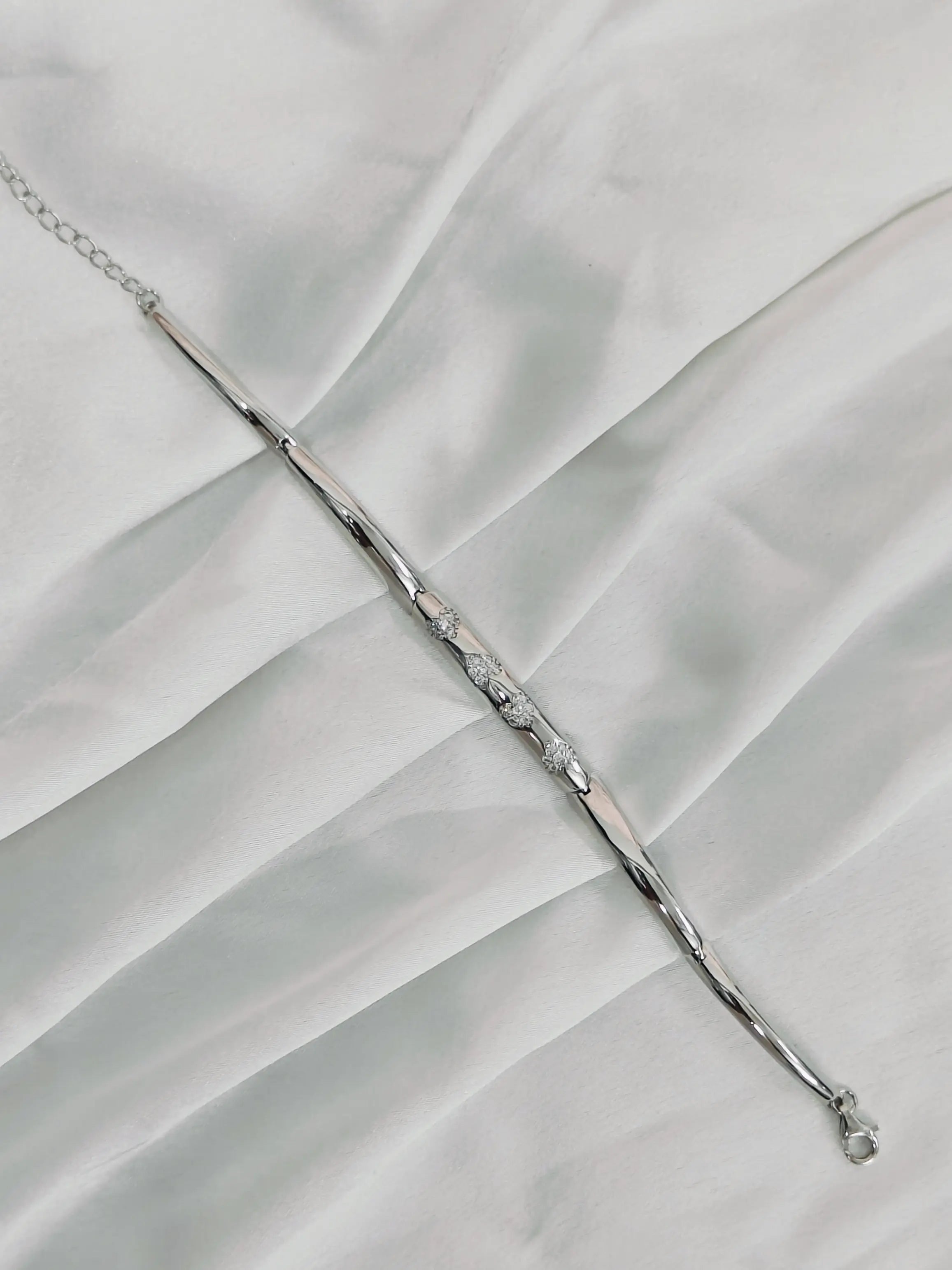 Silver bracelet with small stones on a white fabric background