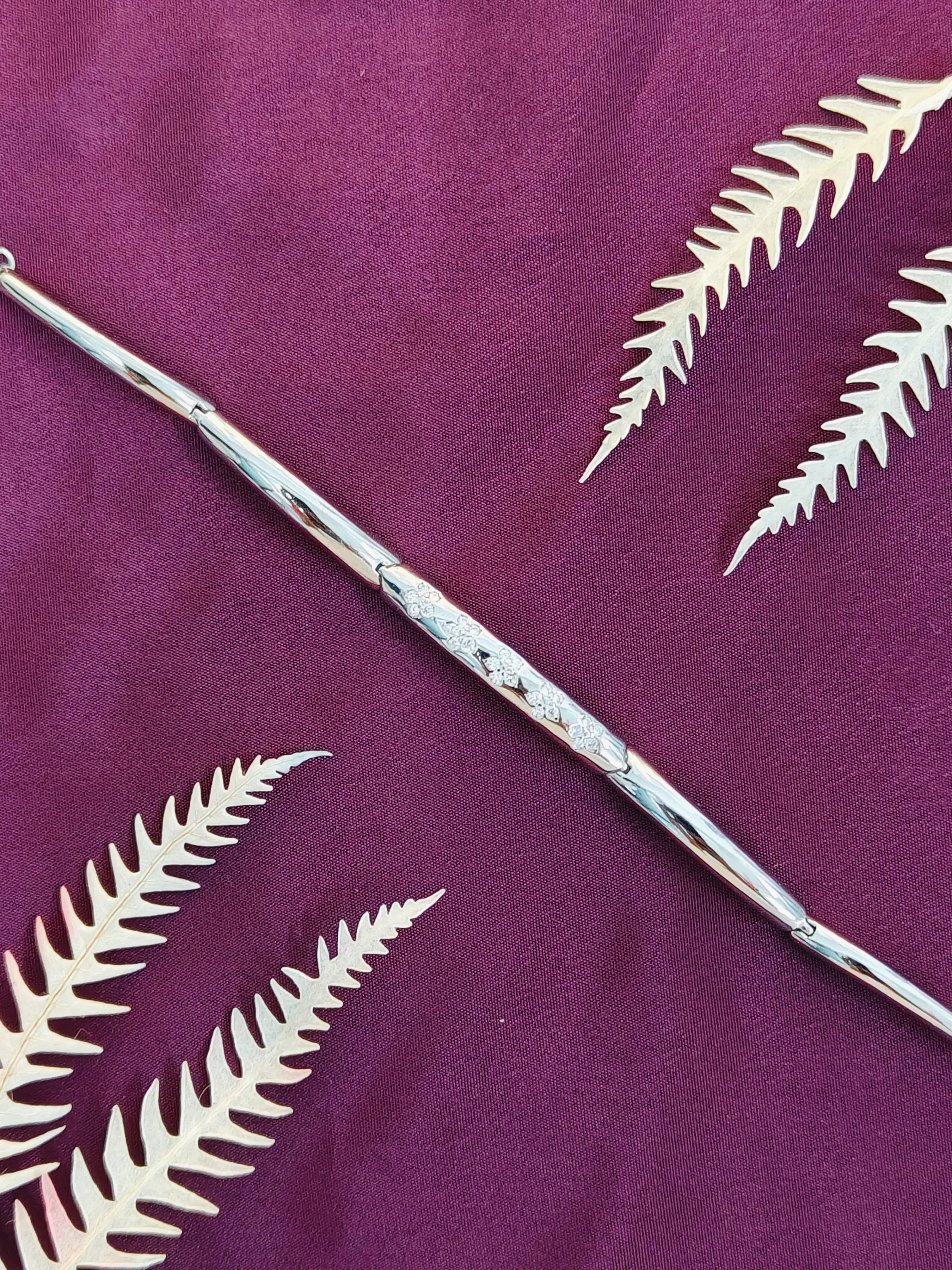 Silver wand with white leaf patterns on a purple background