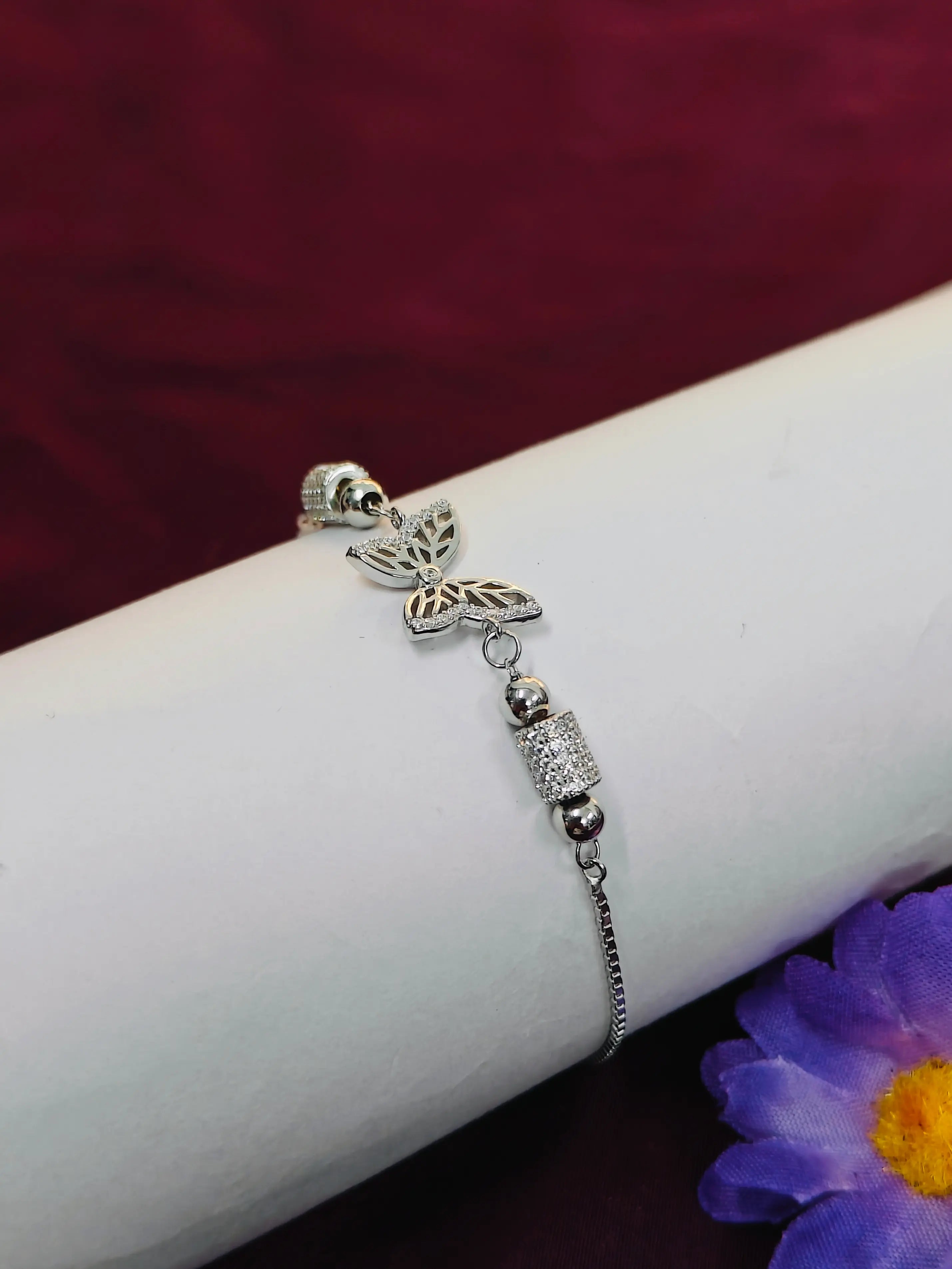Silver bracelet with butterfly charm on a wrist against a dark background