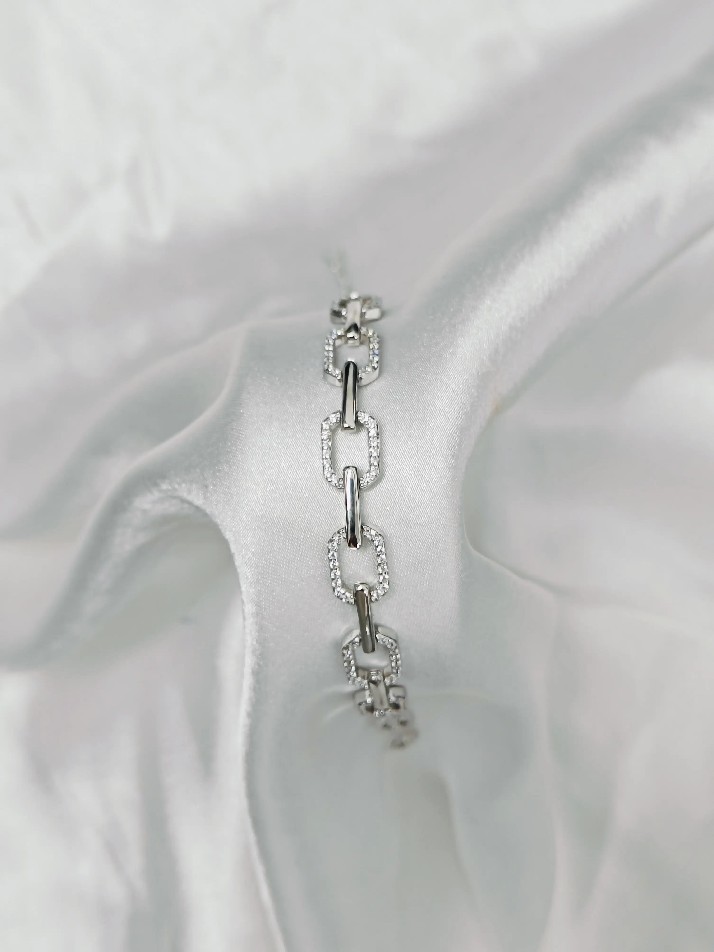 Silver bracelet with clear stones on a white fabric background