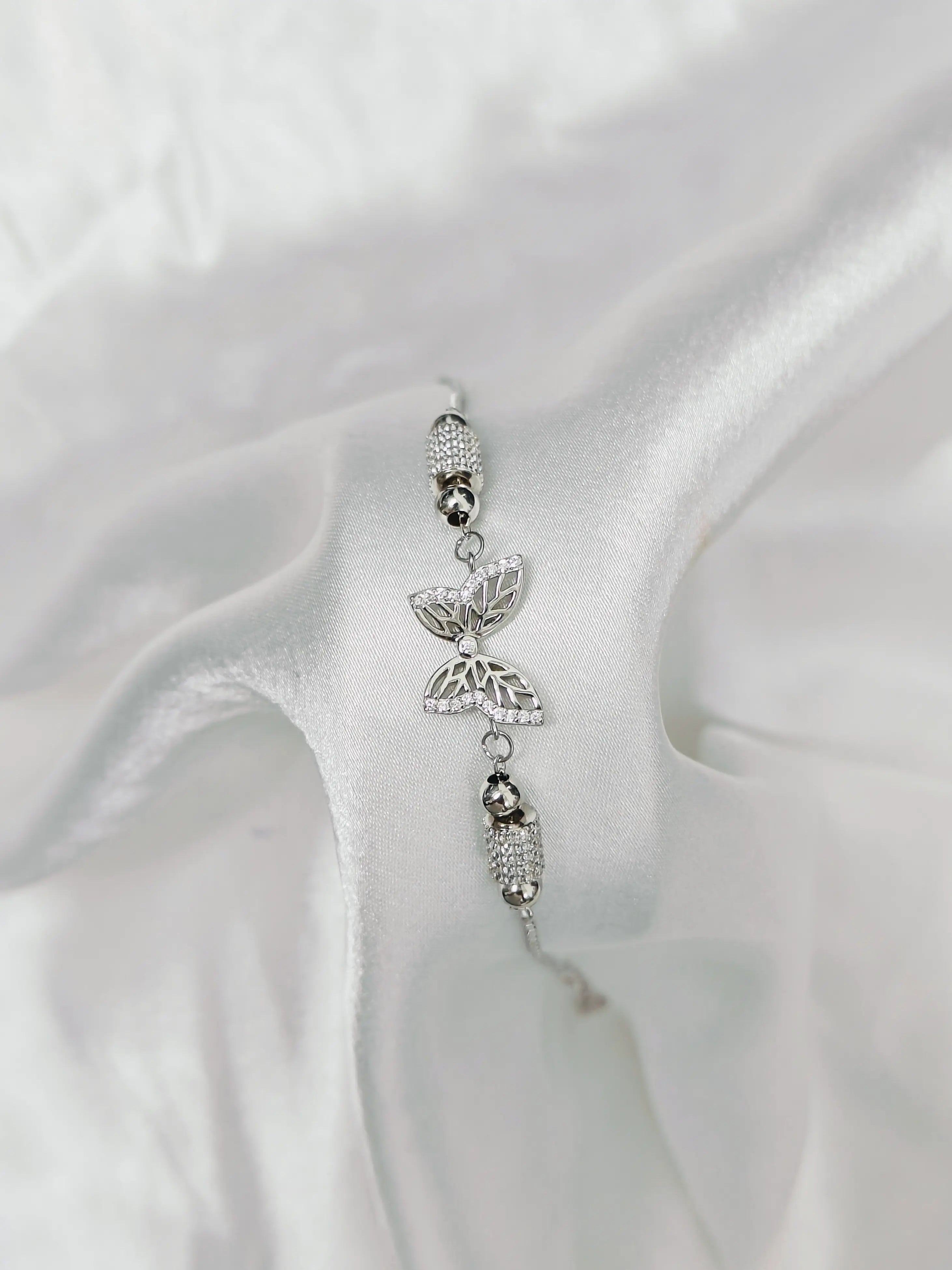 Silver butterfly charm on a white satin background