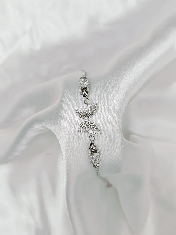 Silver butterfly charm on a white satin background