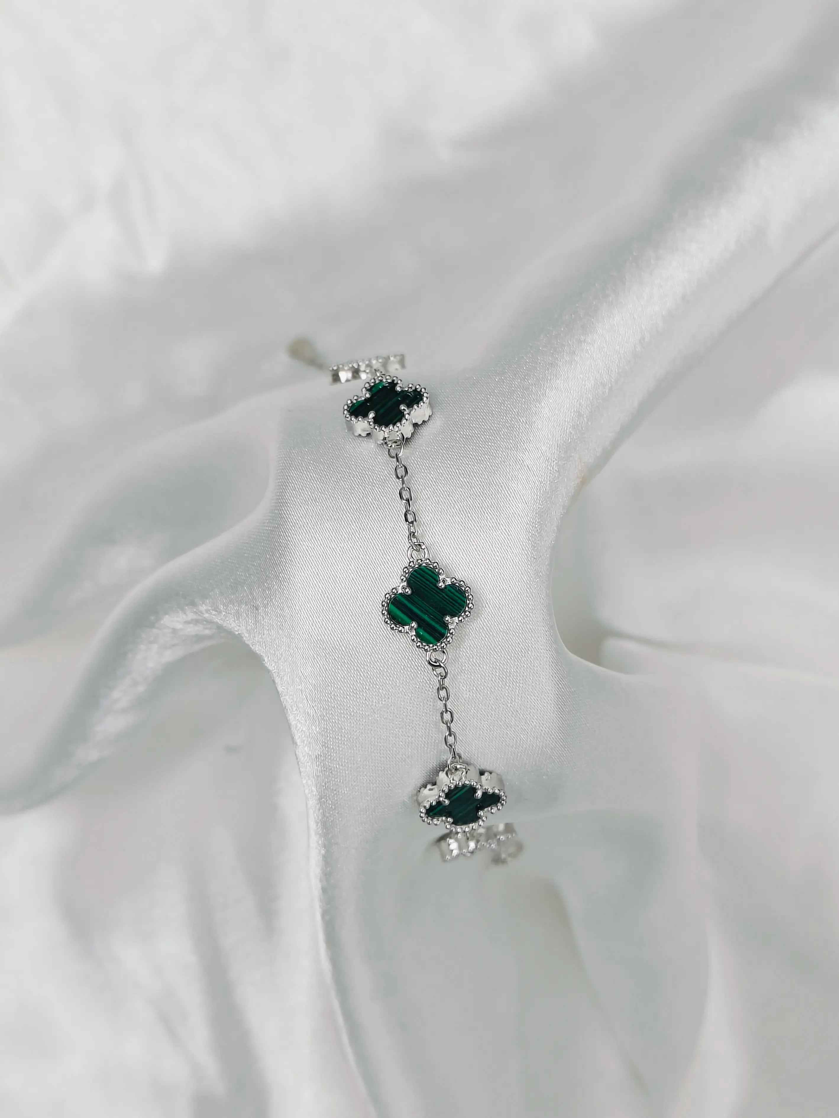 Pair of earrings with green gemstones on a white fabric background