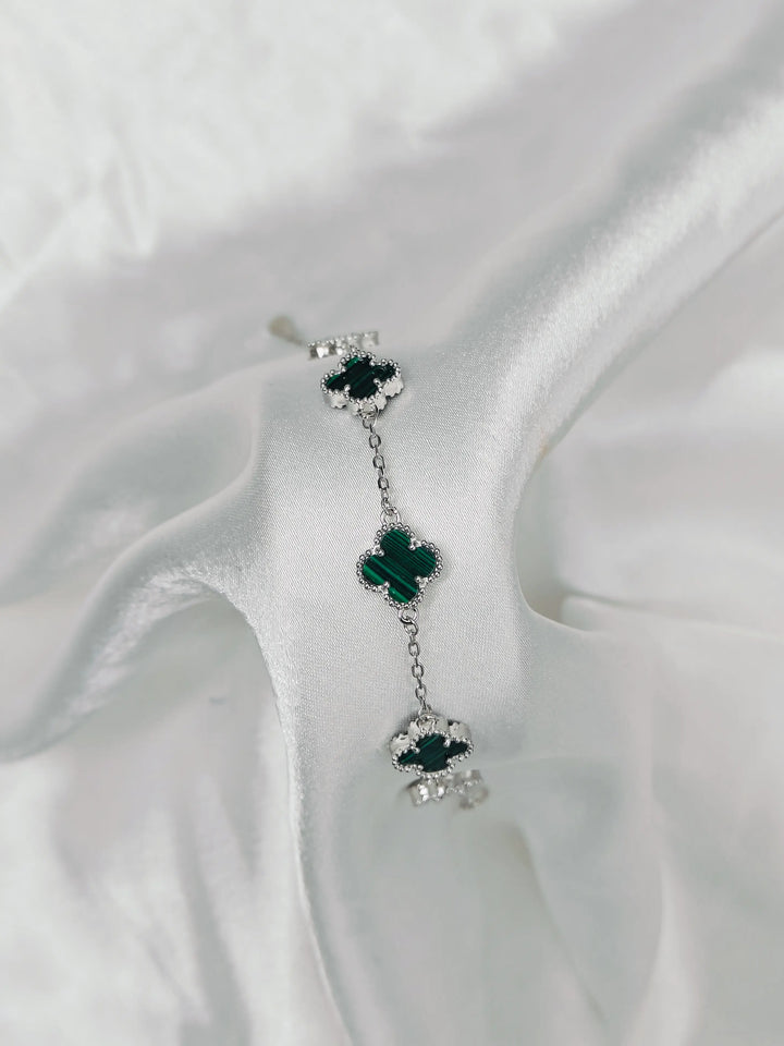 Pair of earrings with green gemstones on a white fabric background