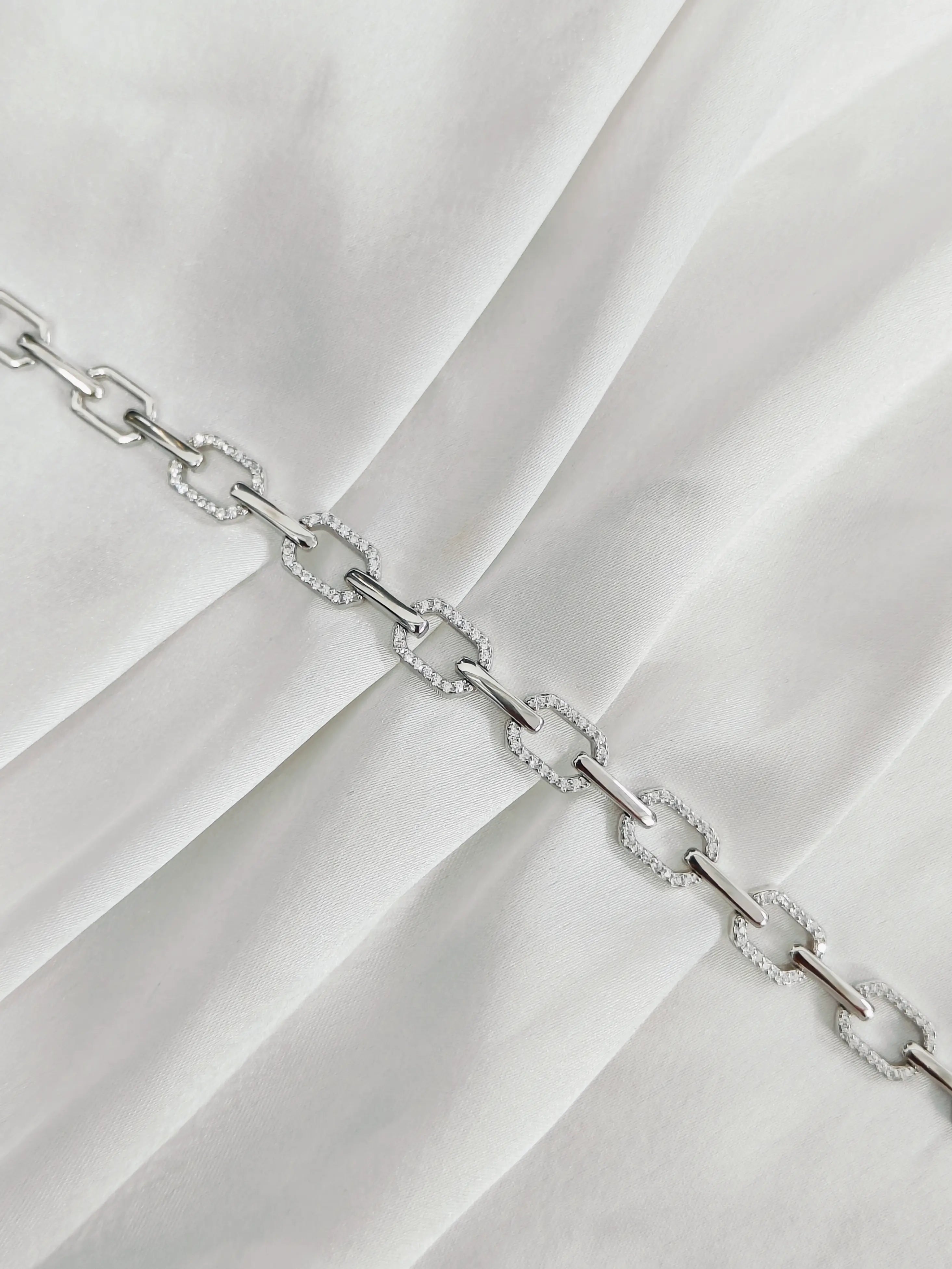 Silver chain bracelet on a white fabric background