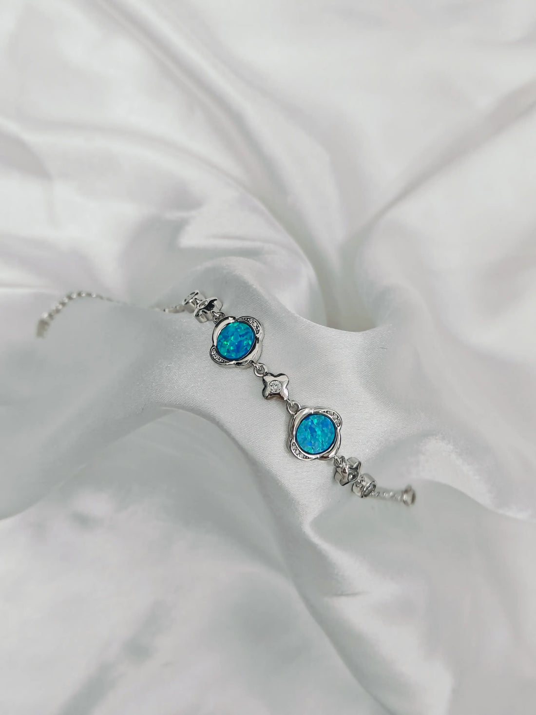 Silver bracelet with blue gemstones on a white fabric background