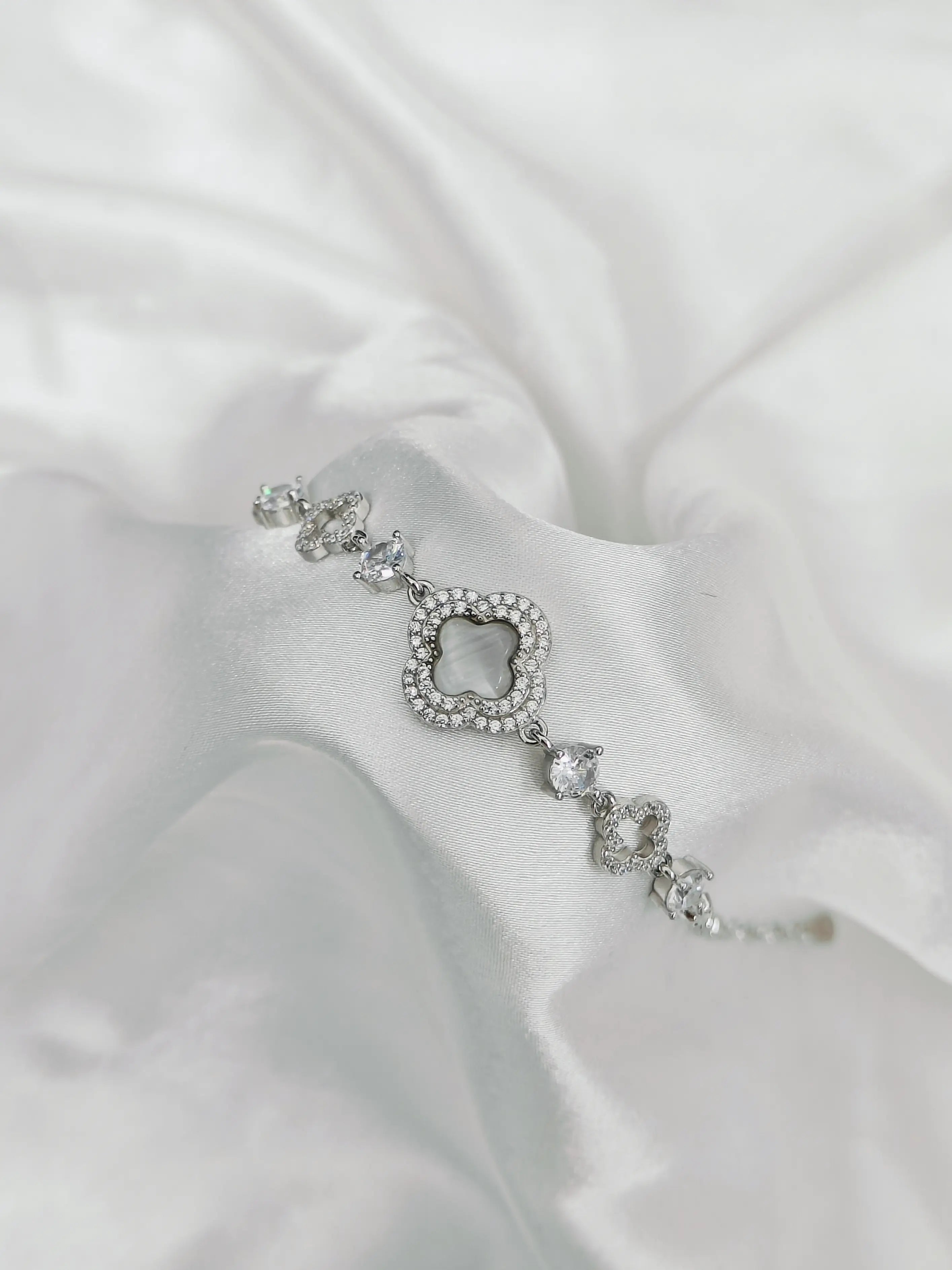 Silver bracelet with clear stones on a white satin background