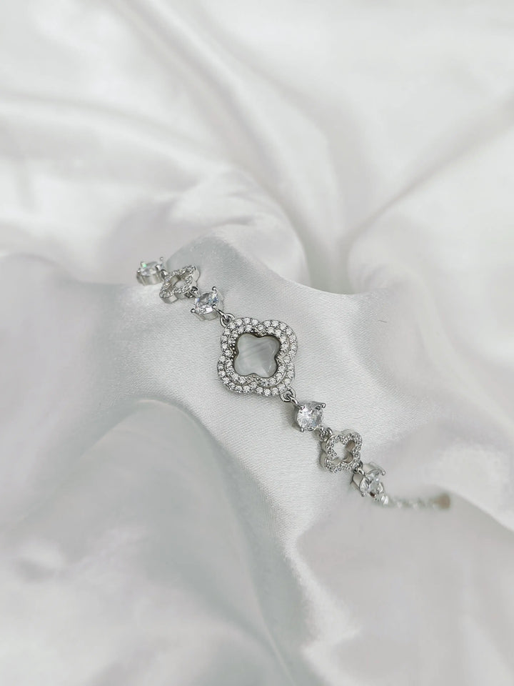Silver bracelet with clear stones on a white satin background