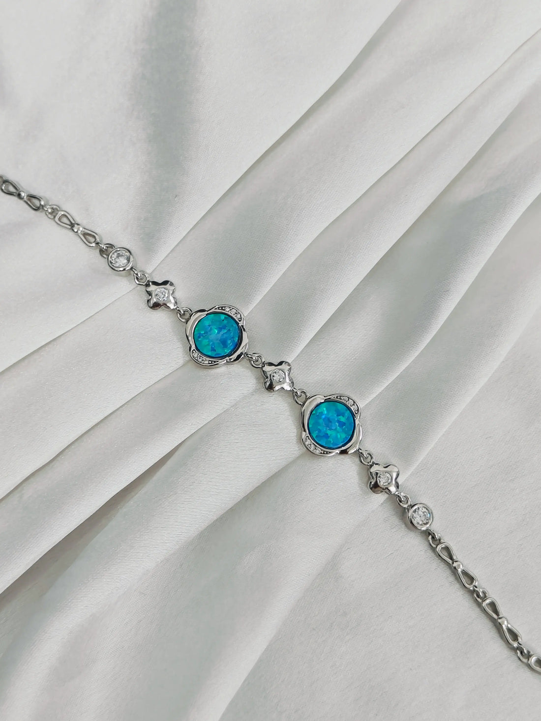 Silver bracelet with blue gemstones on a white fabric background