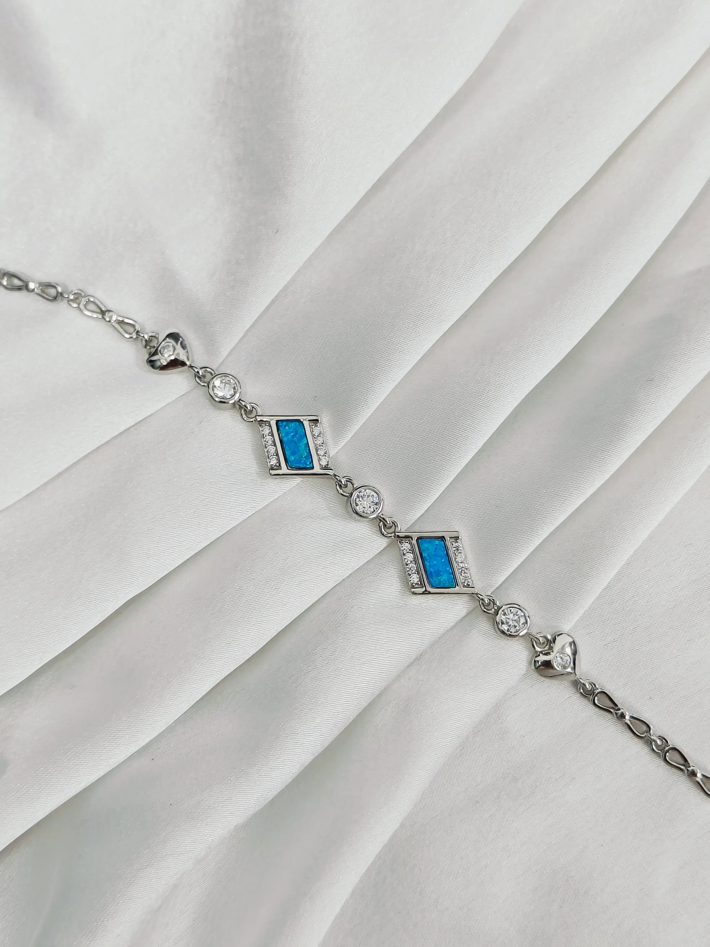 Silver bracelet with blue stones on a white fabric background