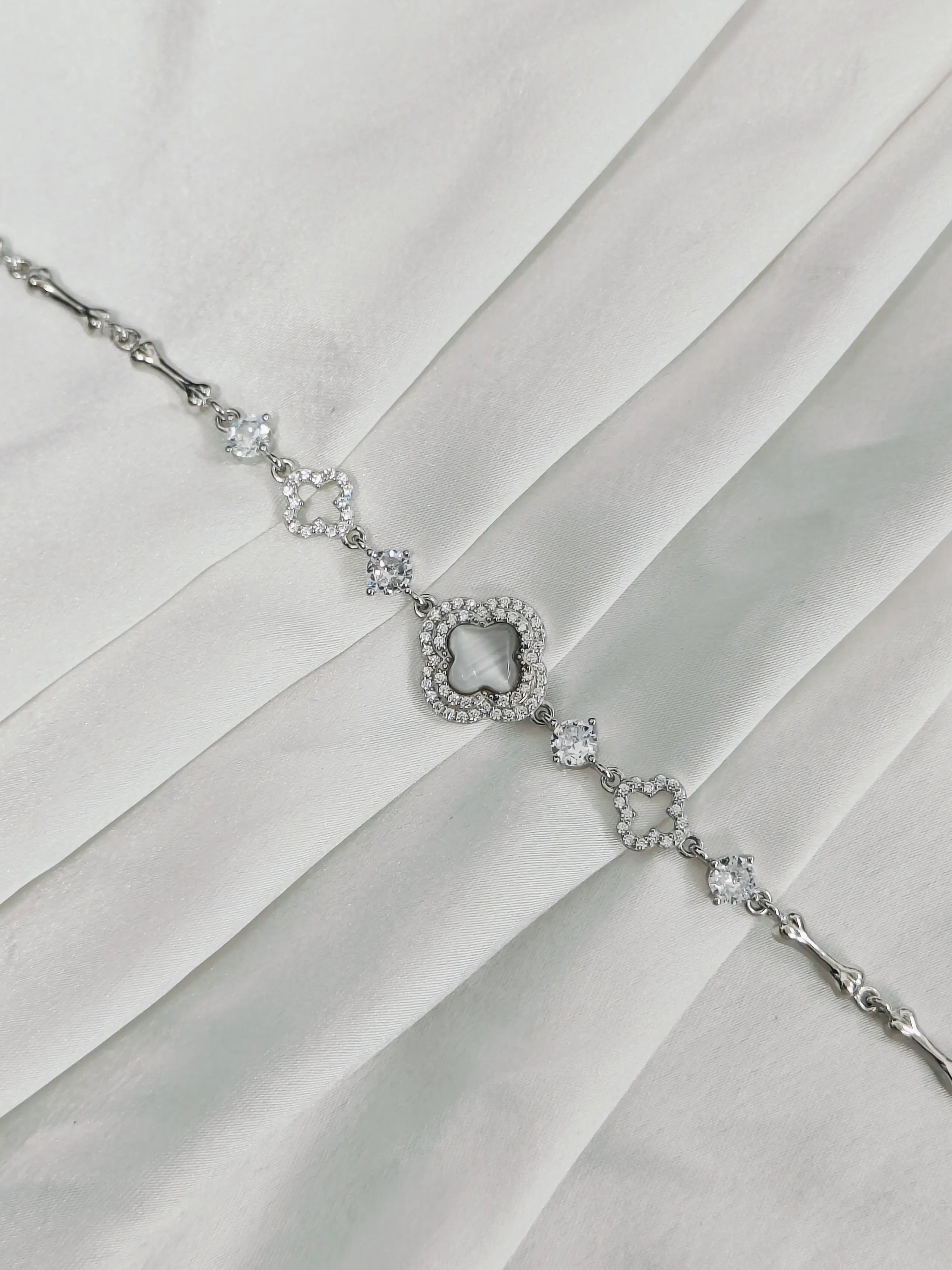 Silver necklace with a star-shaped clasp on a white fabric background