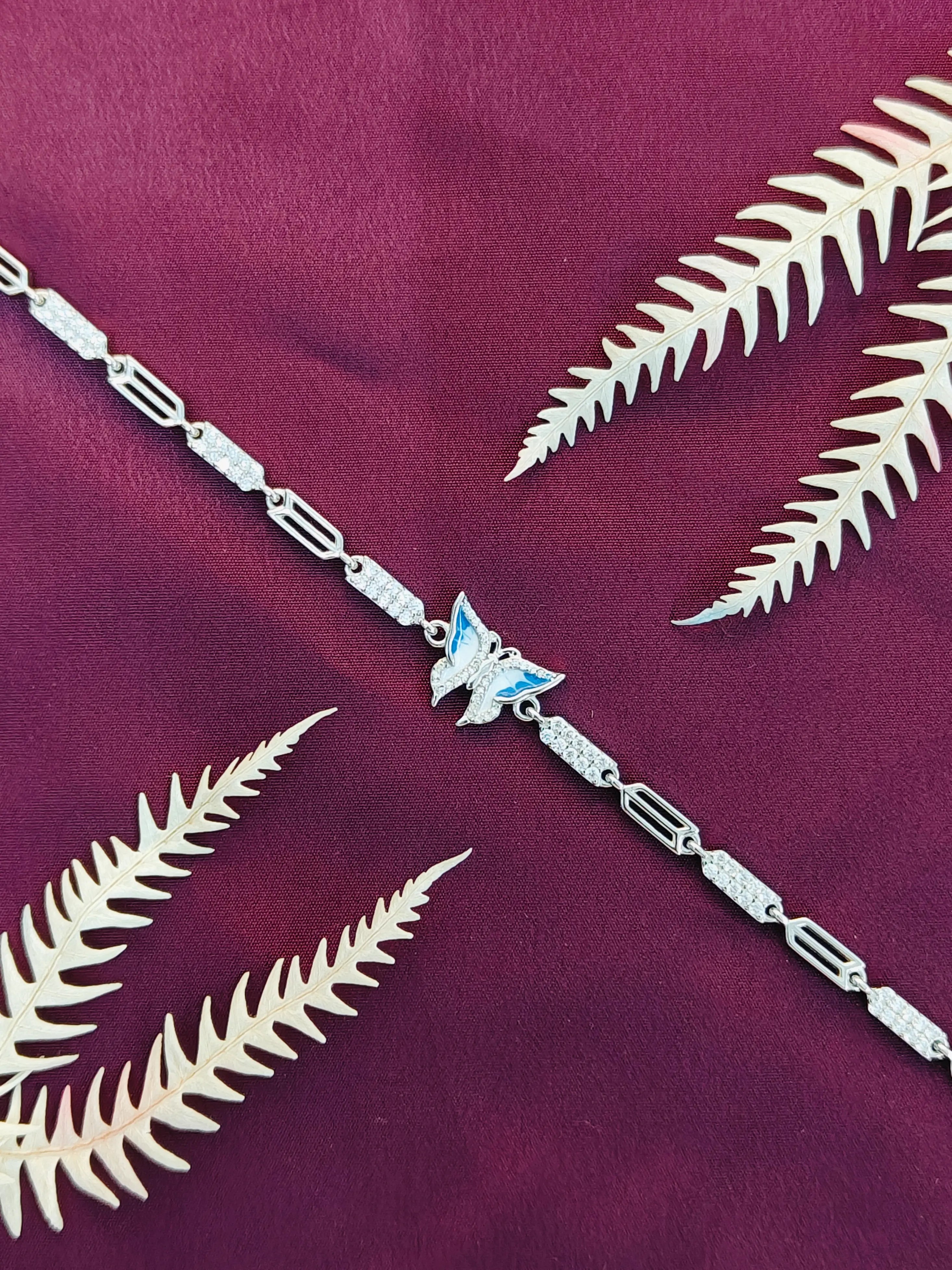 Silver bracelet with butterfly charm on a purple fabric background