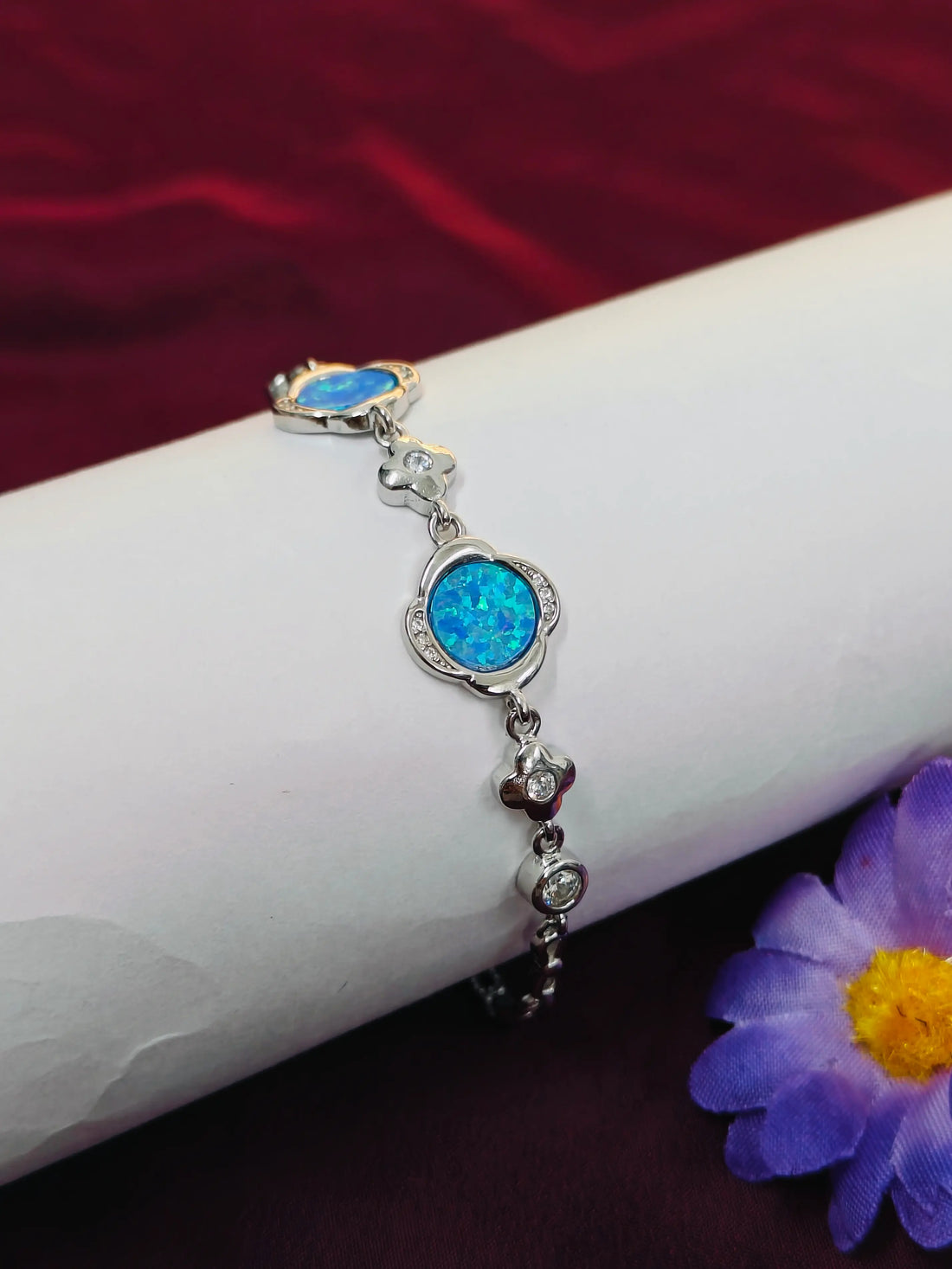 Silver bracelet with blue stones on a white arm against a red background