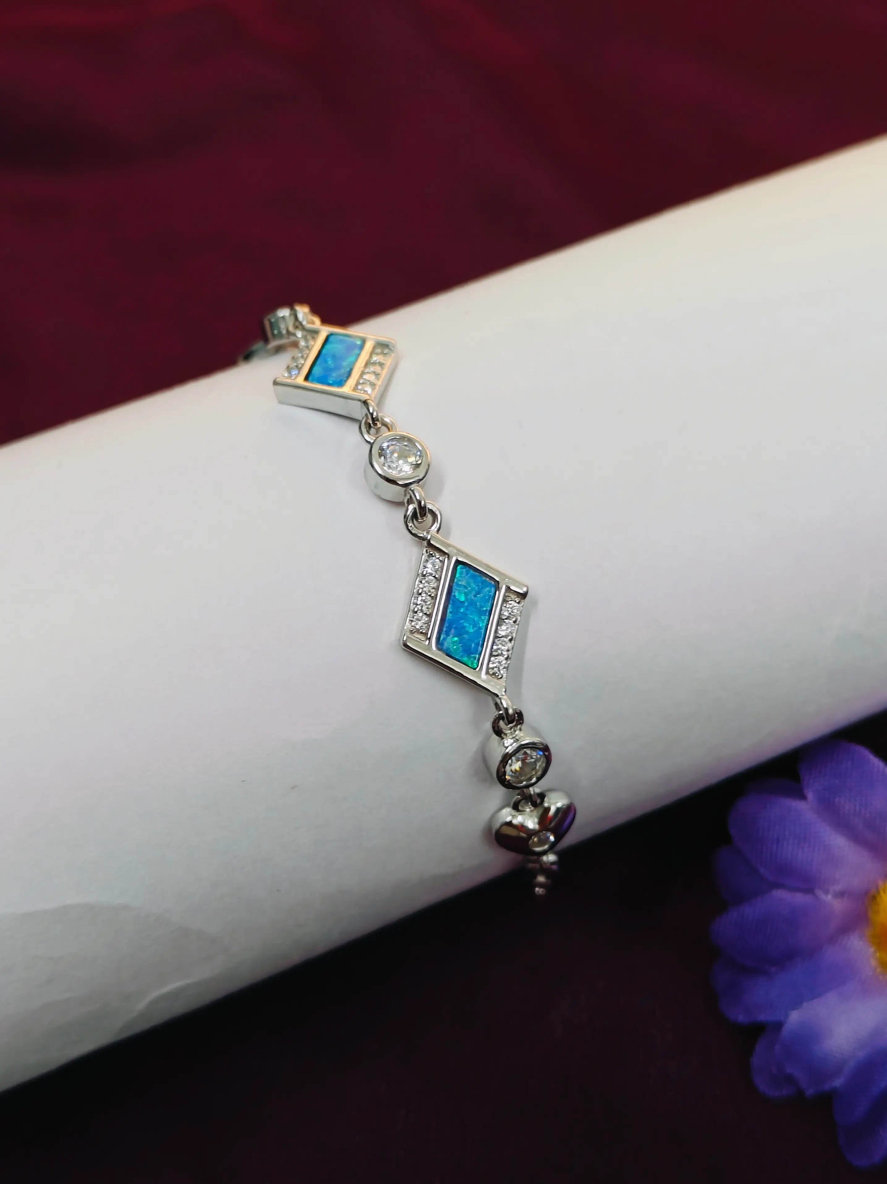 Silver bracelet with blue stones on a wrist against a dark background