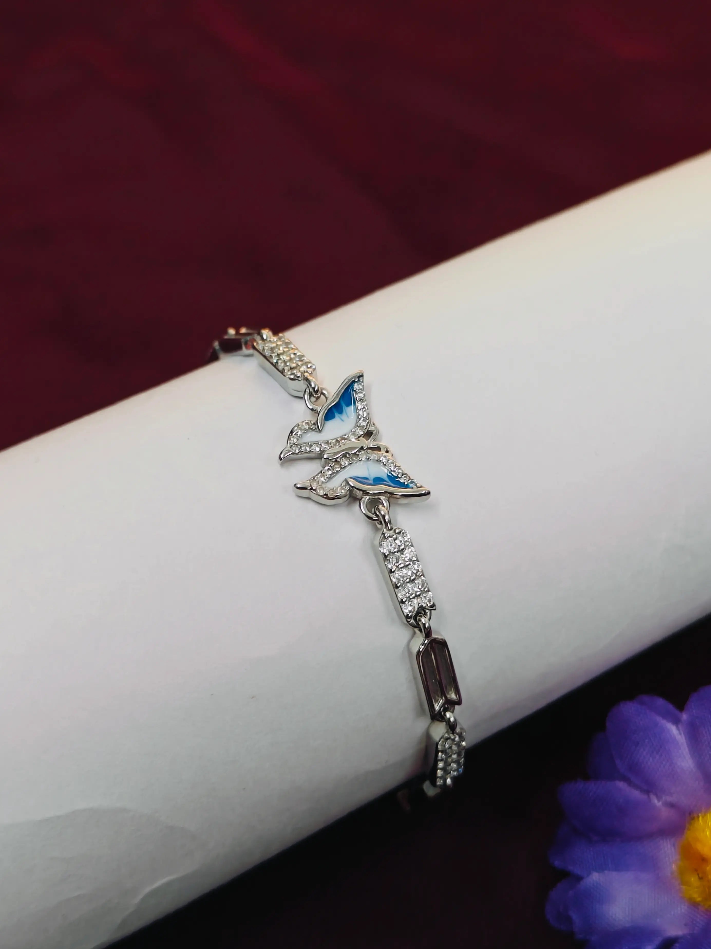 Silver bracelet with butterfly design on a white arm against a dark background