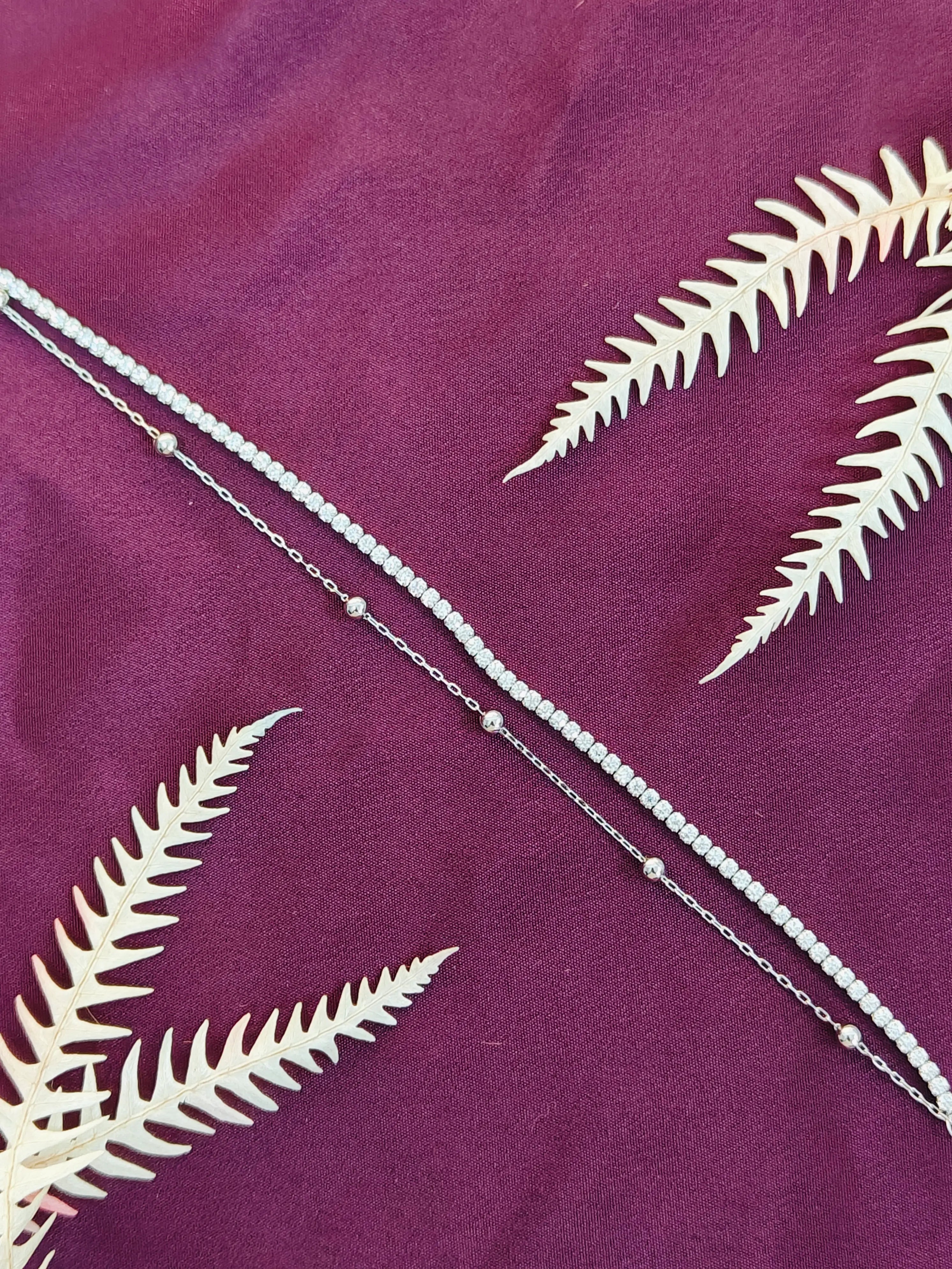 White leaf patterns on a purple fabric background with a silver chain.