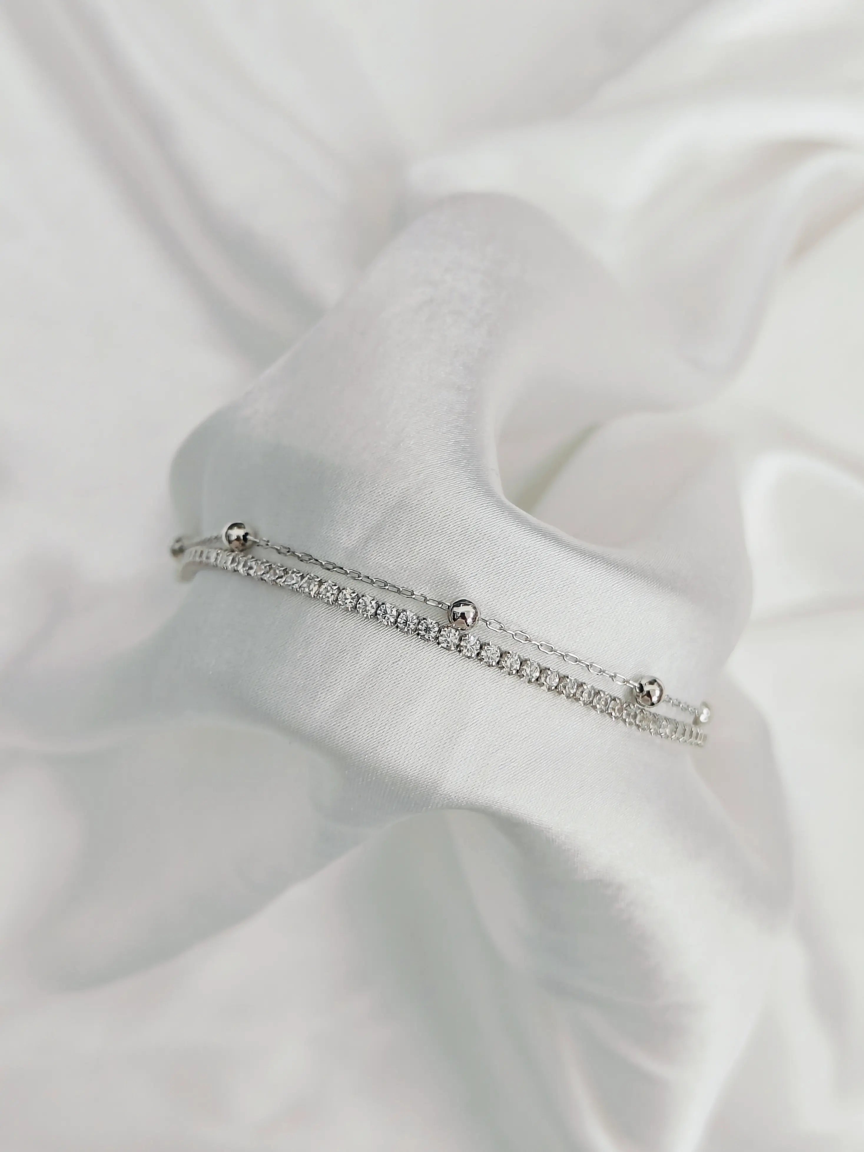 Silver bracelet with small stones on a white fabric background