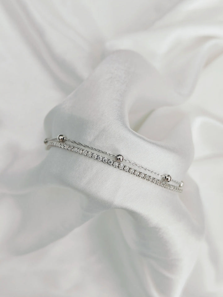 Silver bracelet with small stones on a white fabric background