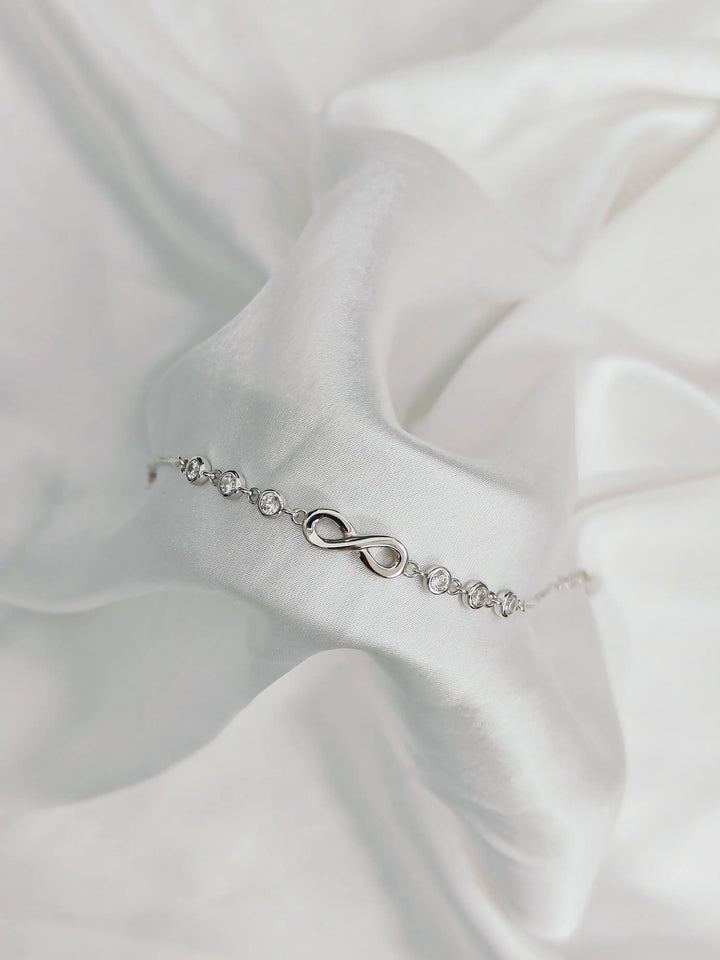 Silver bracelet with an infinity symbol on a white satin background