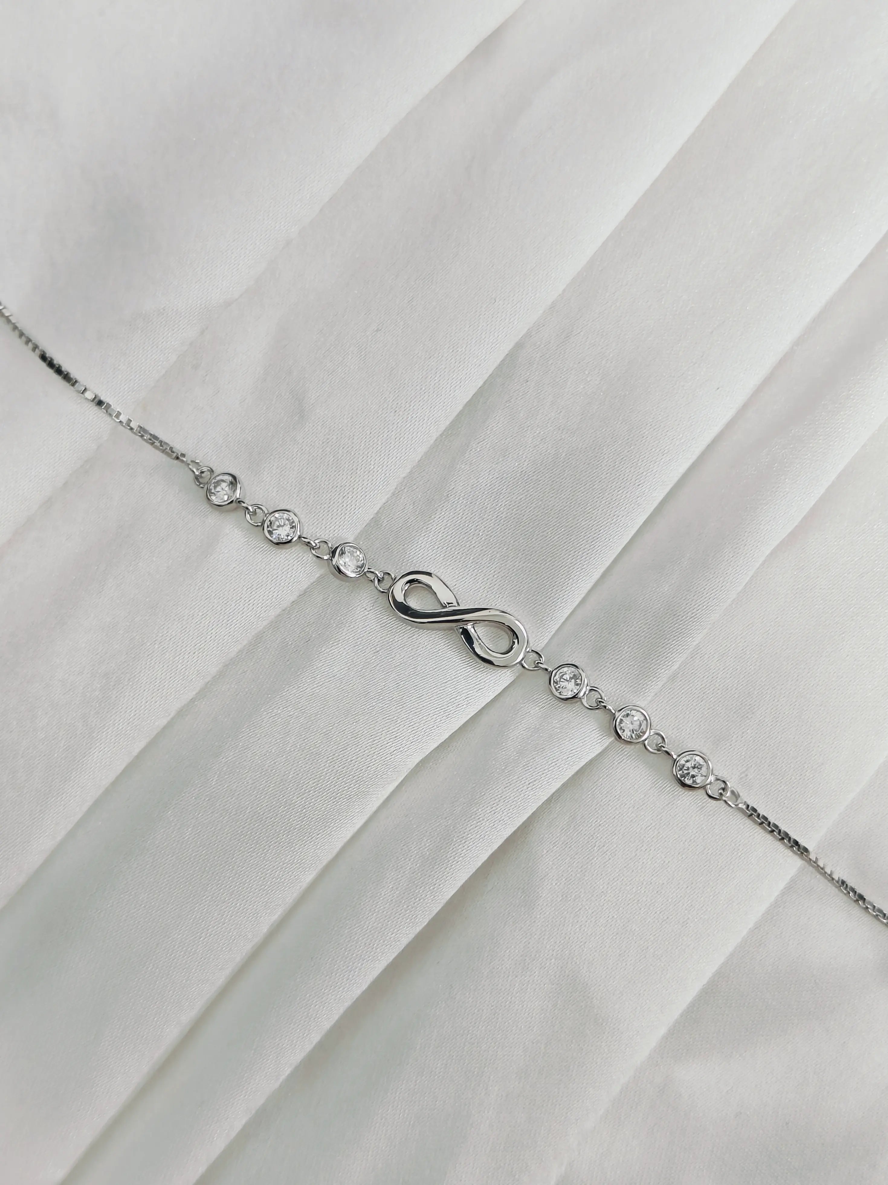 Silver bracelet with an infinity symbol on a white fabric background