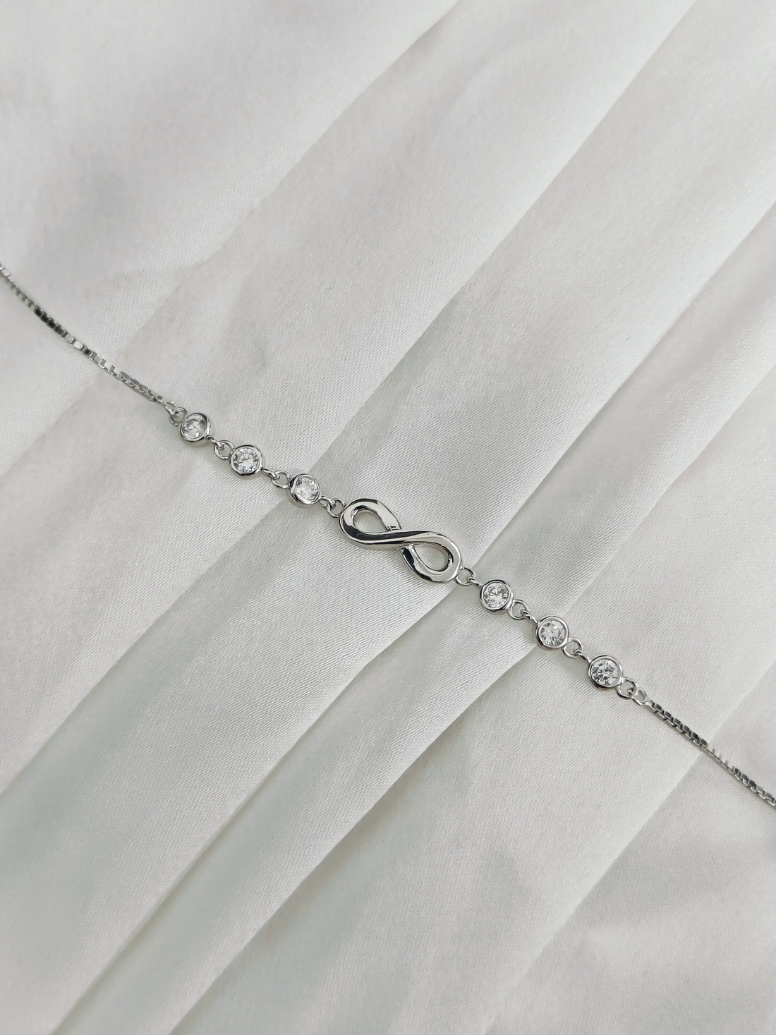 Silver bracelet with an infinity symbol on a white fabric background