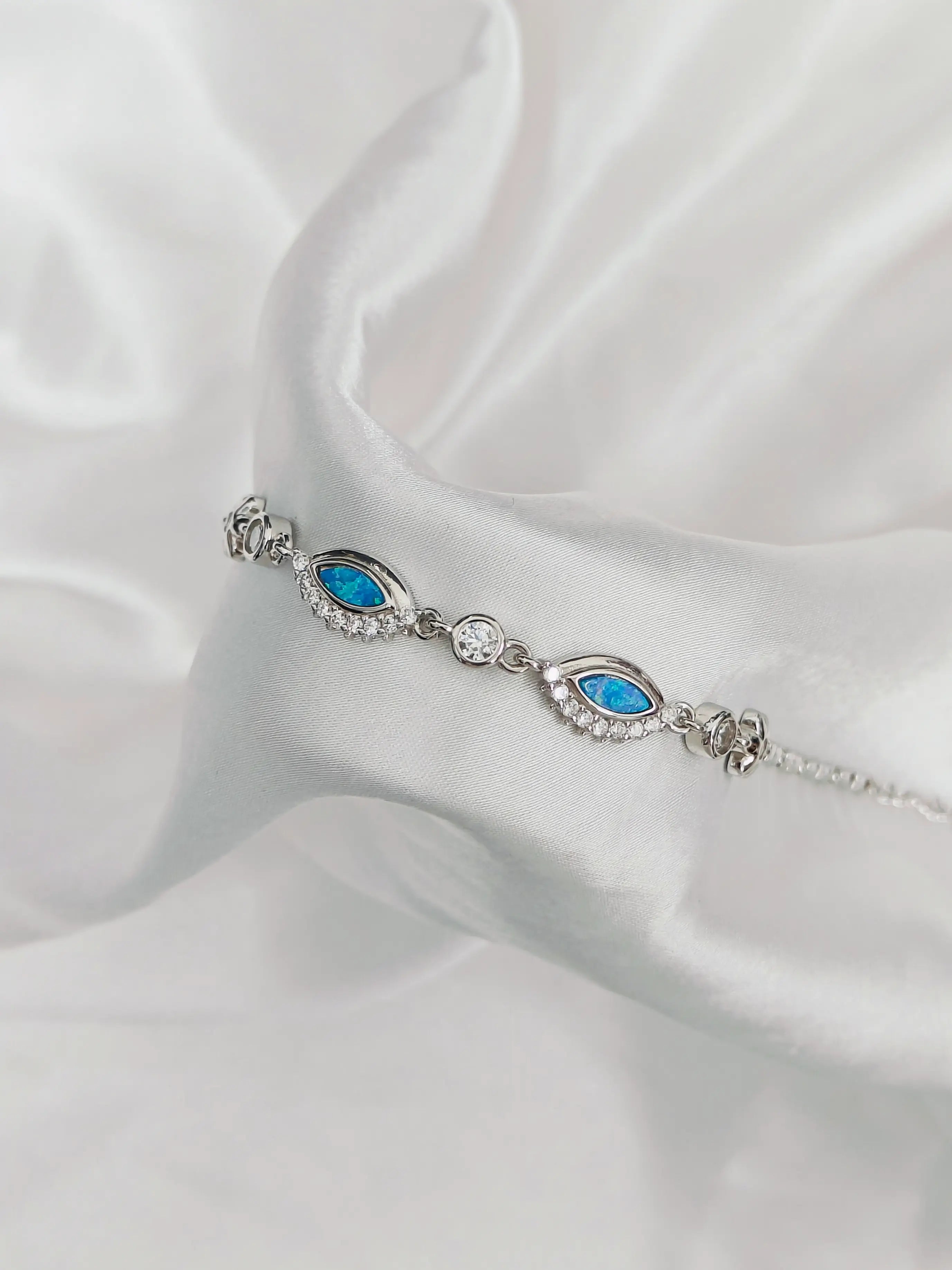 Silver bracelet with blue stones on a white satin background