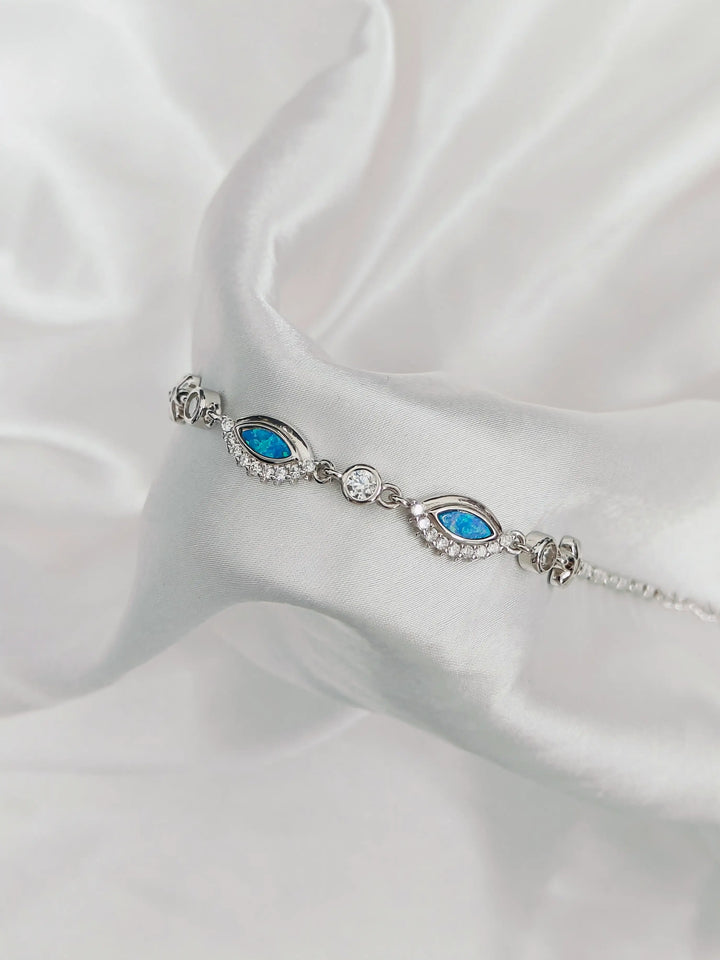 Silver bracelet with blue stones on a white satin background