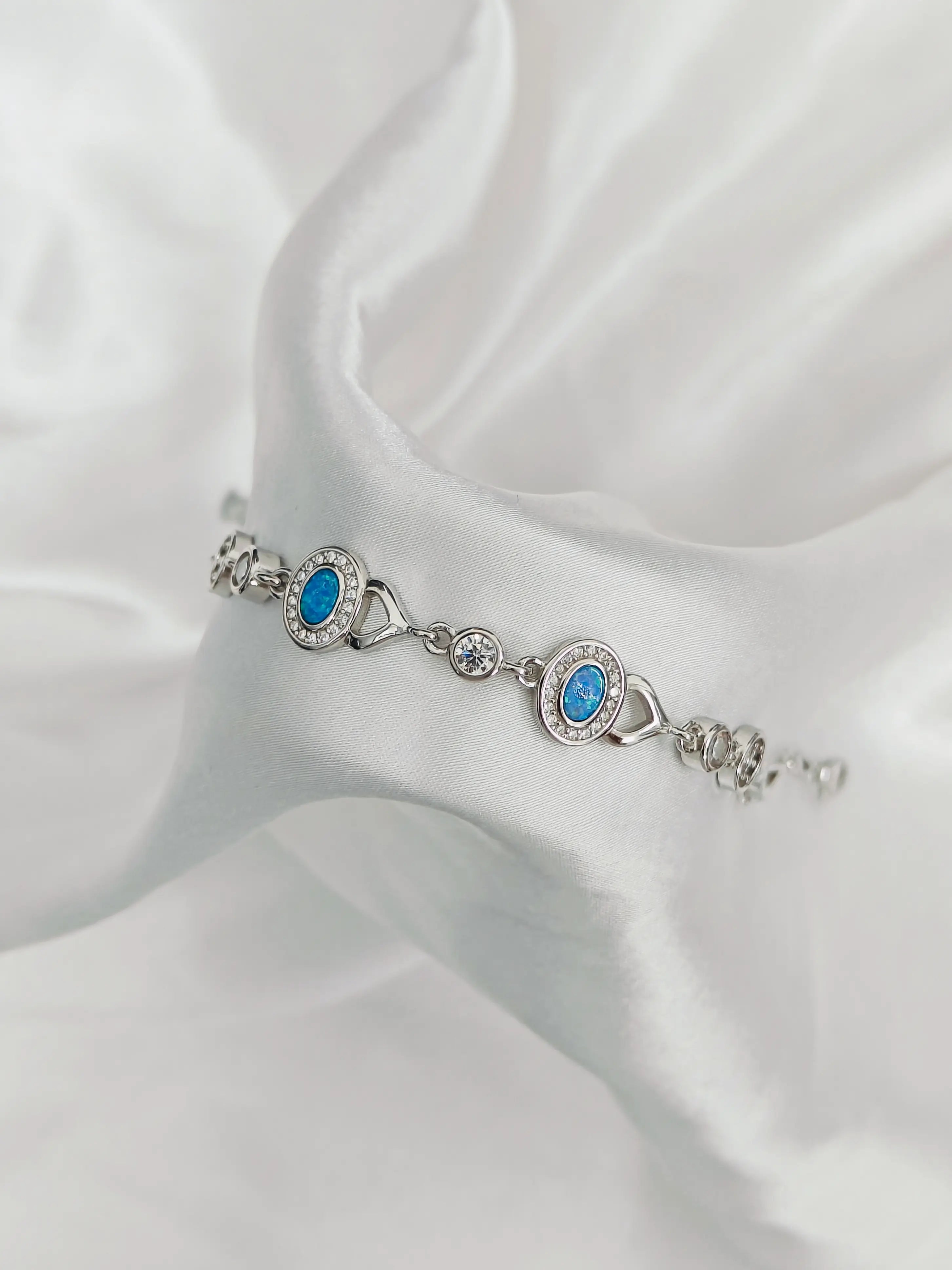 Silver bracelet with blue stones on a white fabric background