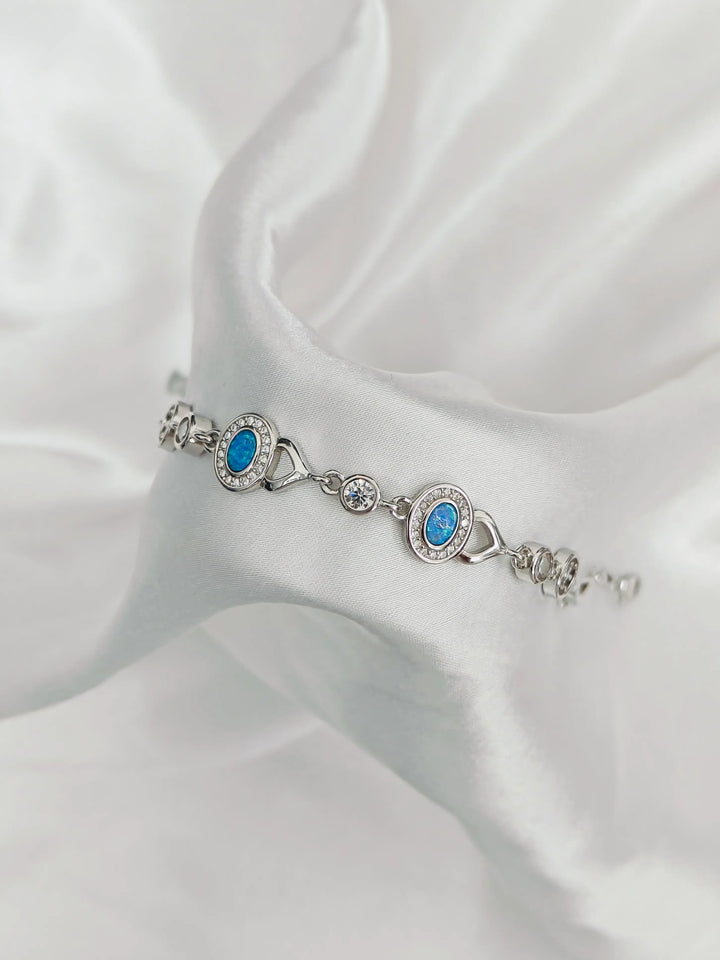 Silver bracelet with blue stones on a white fabric background